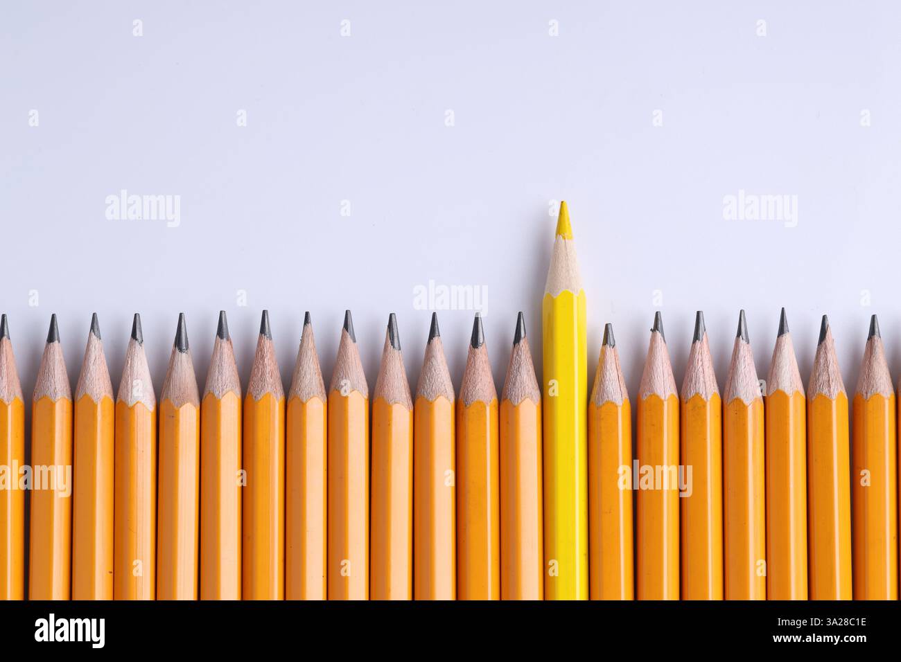 Ein gelber Bleistift unter den Graphitstiften auf hellgrauem Hintergrund, Draufsicht. Leerzeichen für Text Stockfoto