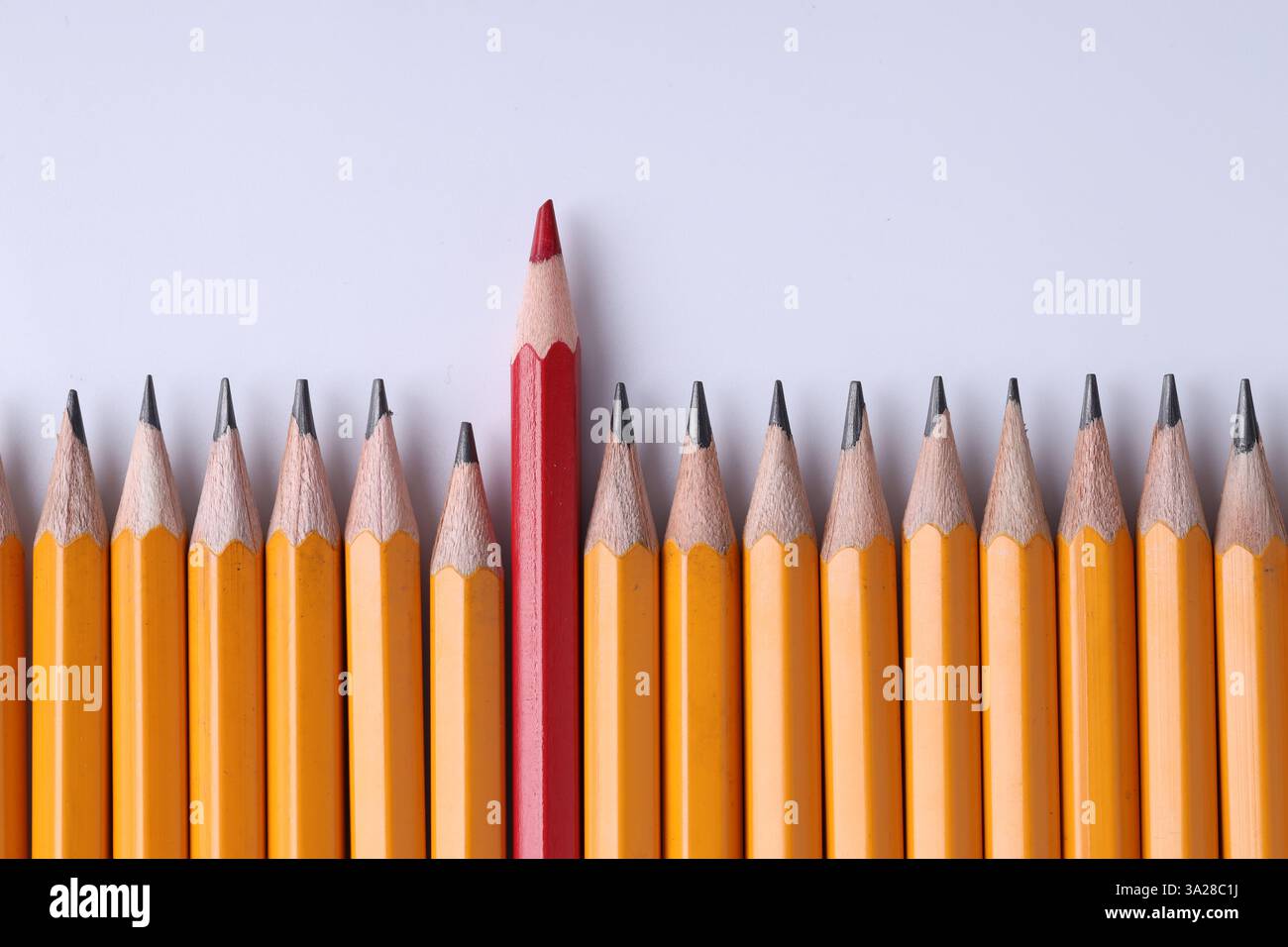 Ein roter Bleistift unter Graphit auf hellgrauem Hintergrund, Draufsicht Stockfoto