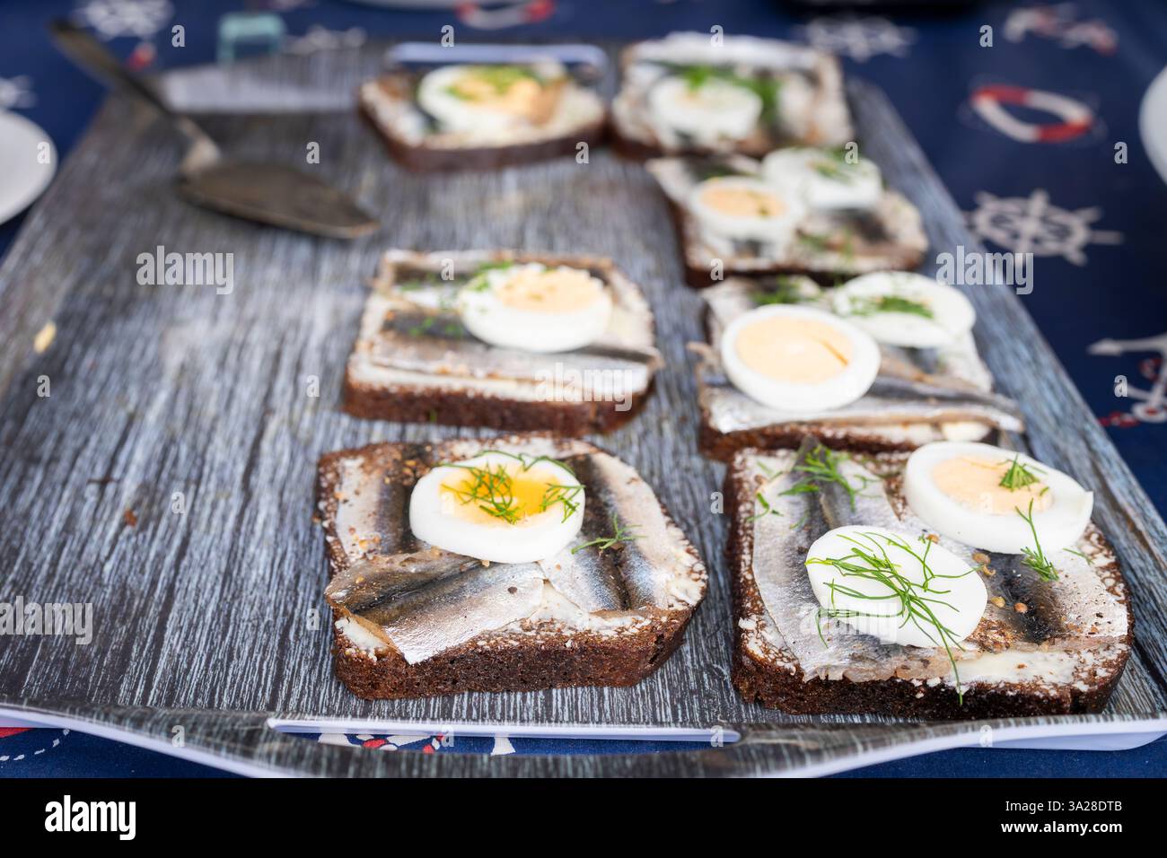 Sandwich mit gewürzter Sprotte: Estnische Sandwich mit würziger gesalzener Sprotte, Butter, gekochtem Ei, frischem Dill auf einer Scheibe nationalem Roggenbrot. Stockfoto