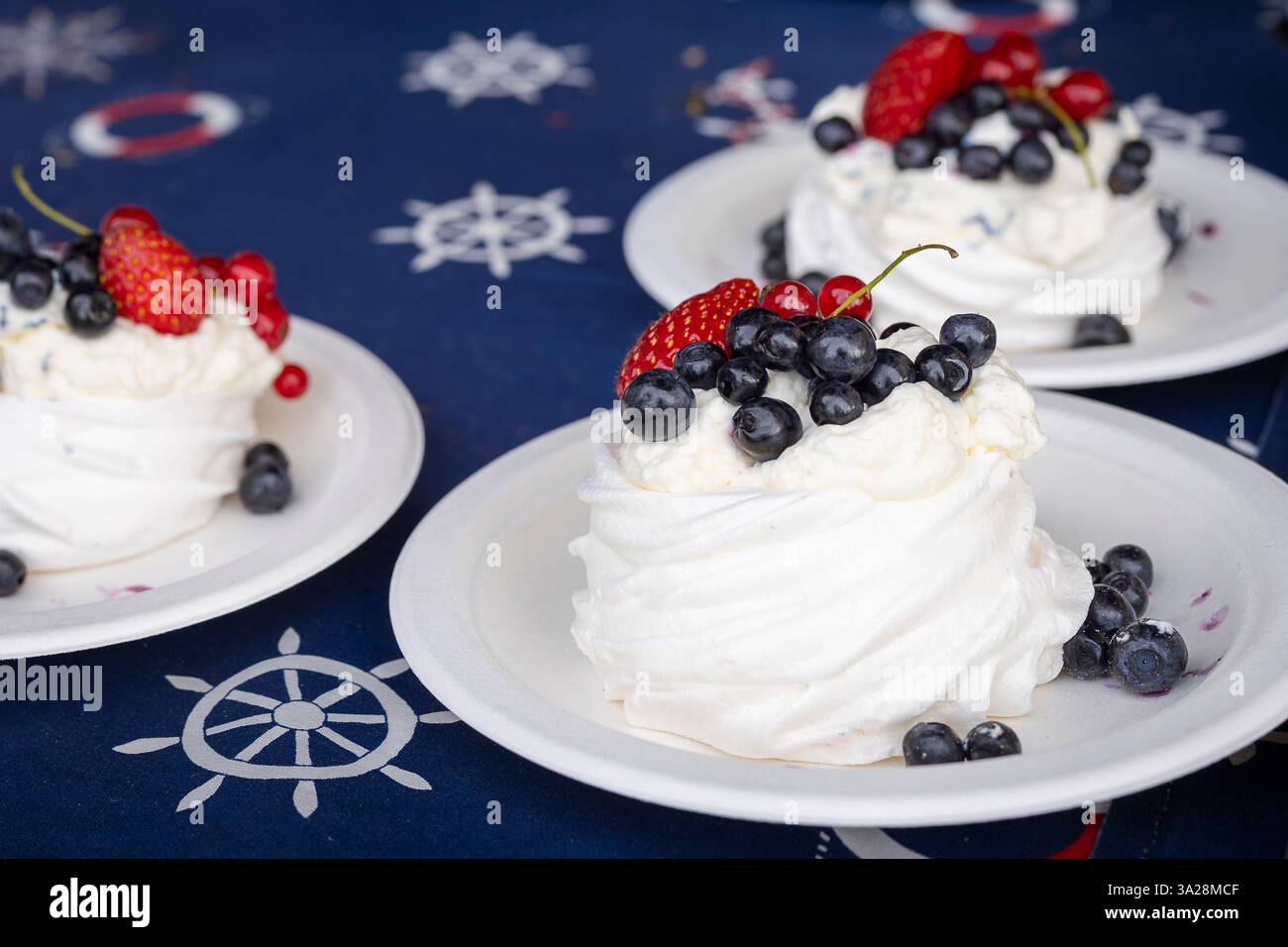 Mini-Pavlova-Kuchen mit Erdbeere, Heidelbeere und roter Johannisbeere auf dunklem Hintergrund. Nachtisch auf Meringue-Basis. Mini Pavlova mit Erdbeere und Heidelbeere. Stockfoto