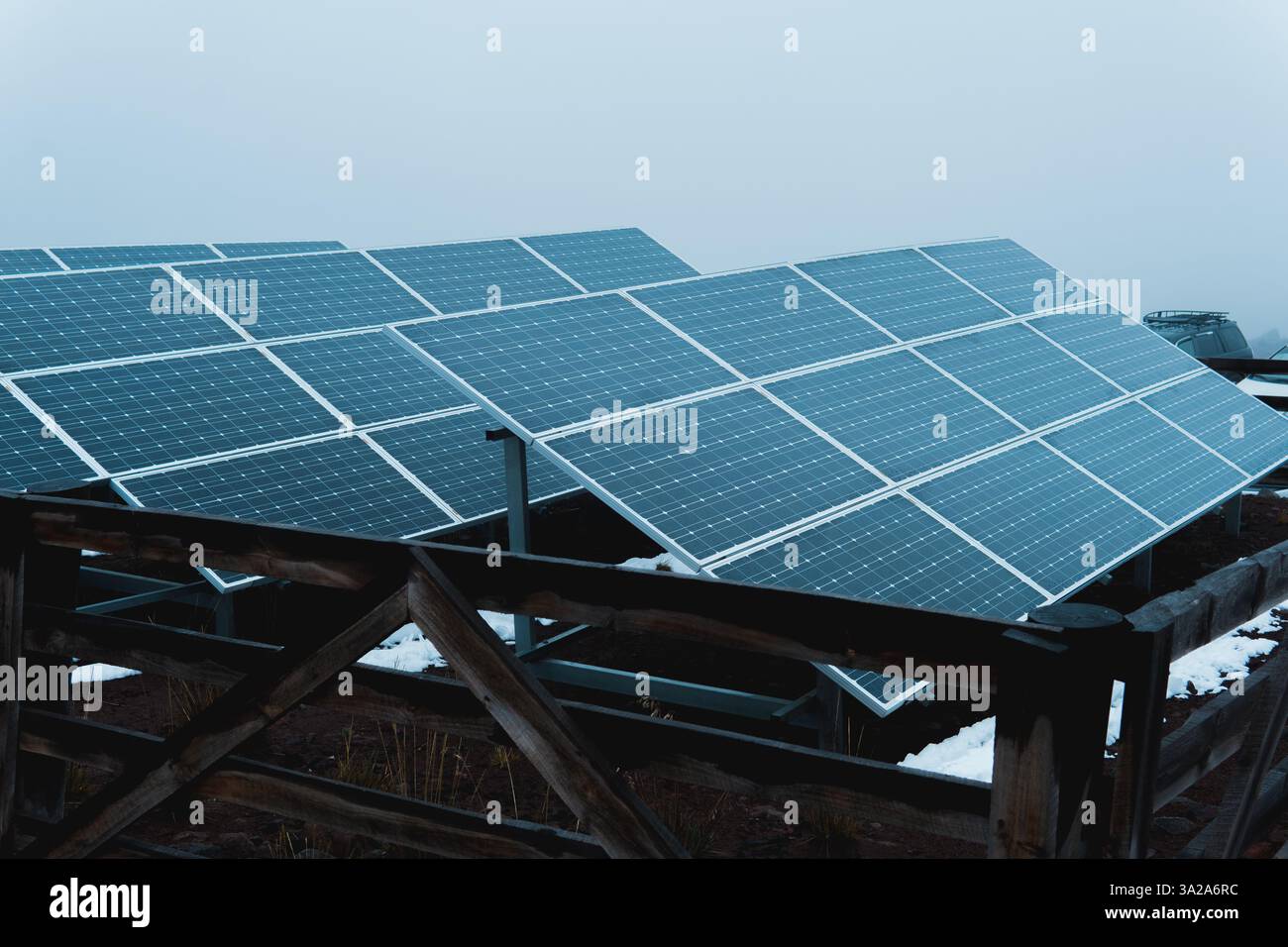 Reihen von Solarpaneelen erfassen Sonnenlicht in einer verschneiten Bergwelt und erzeugen saubere und nachhaltige Energie Stockfoto
