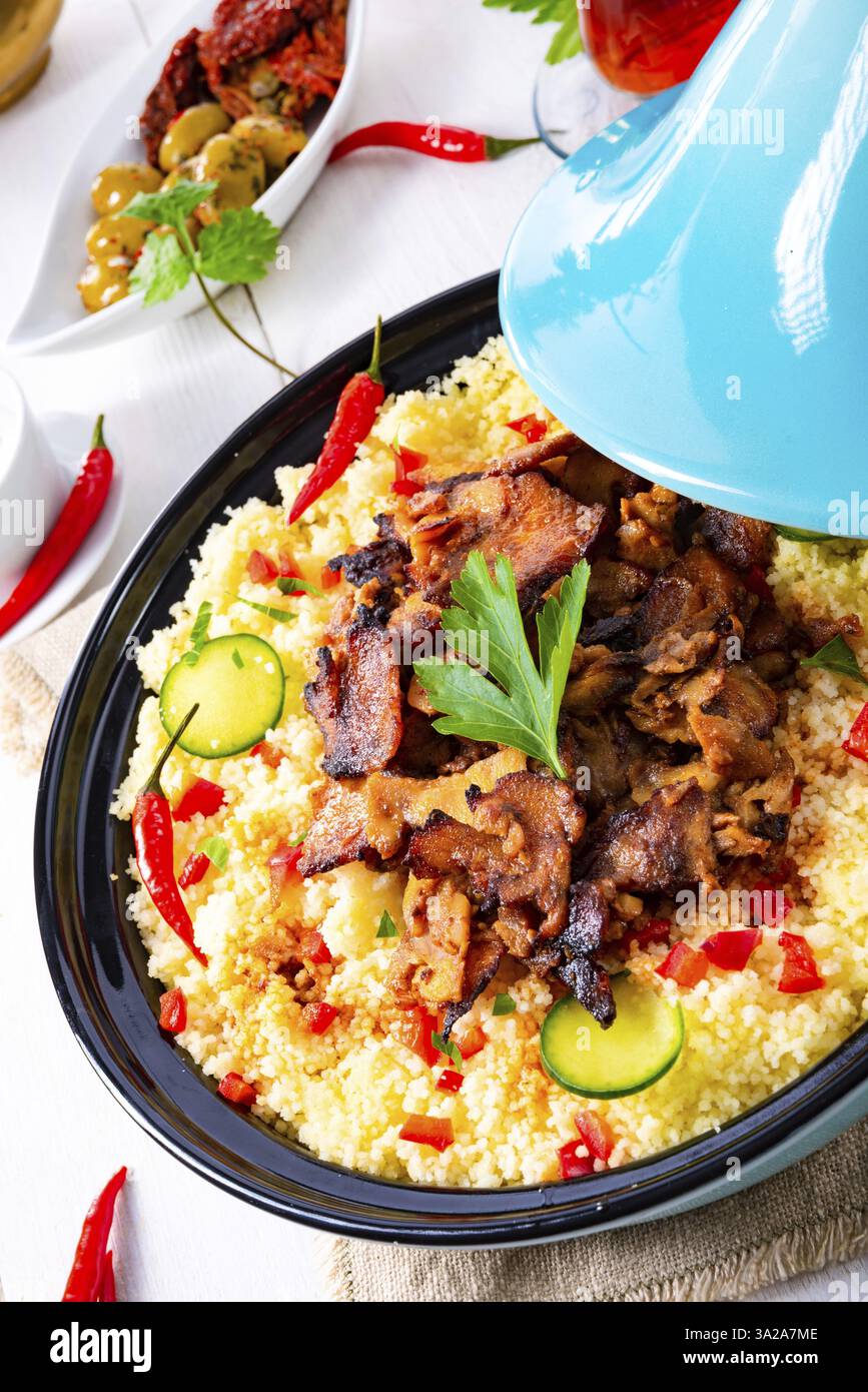 Tajin mit Couscous, Gemüse und Fleisch auf weißem Hintergrund Stockfoto