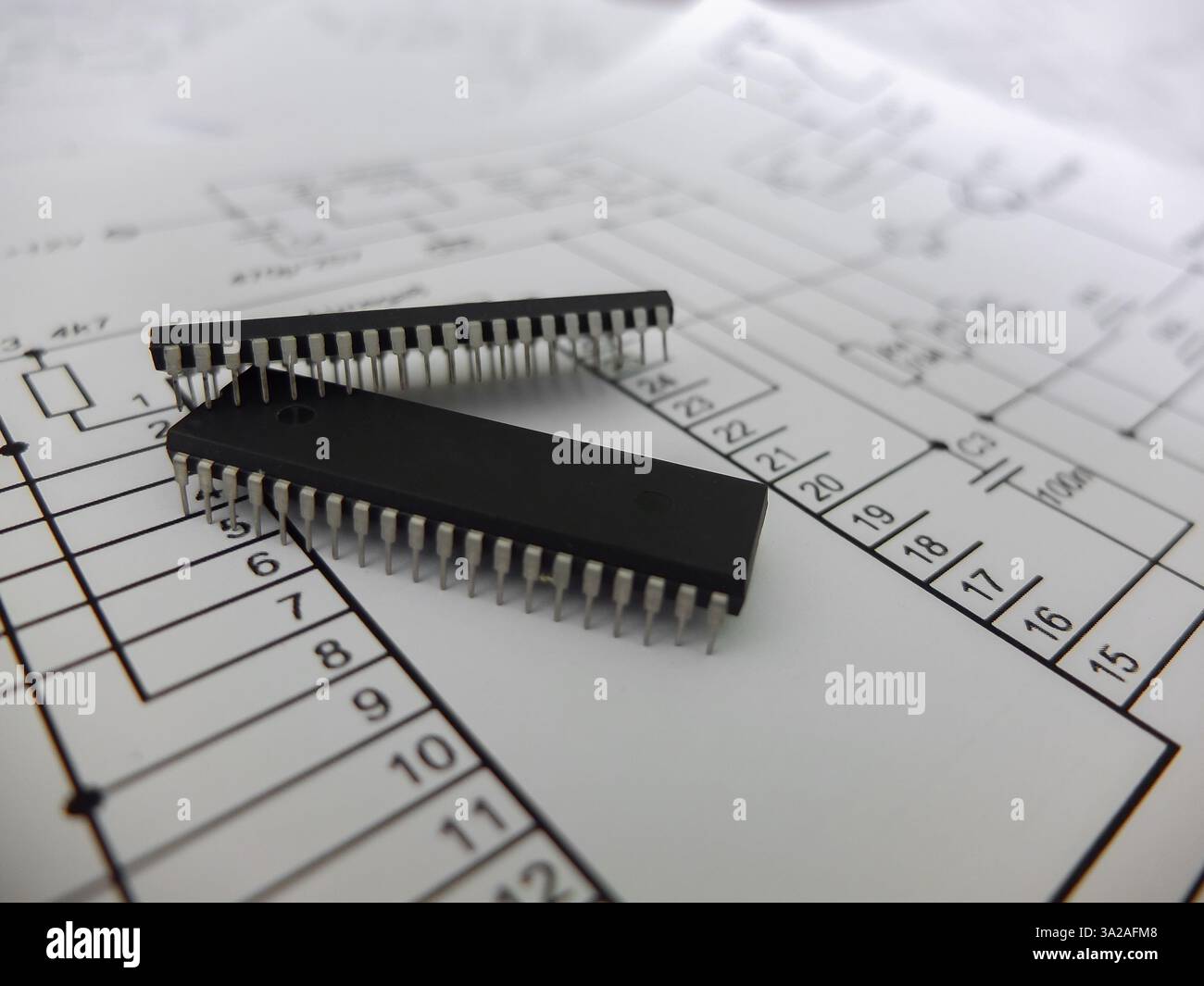 Verschiedene integrierte Schaltungen, Mikrocontroller in DIP-SOIC-TQFP-Gehäusen. Auf der Rückseite befindet sich ein Schaltplan Stockfoto