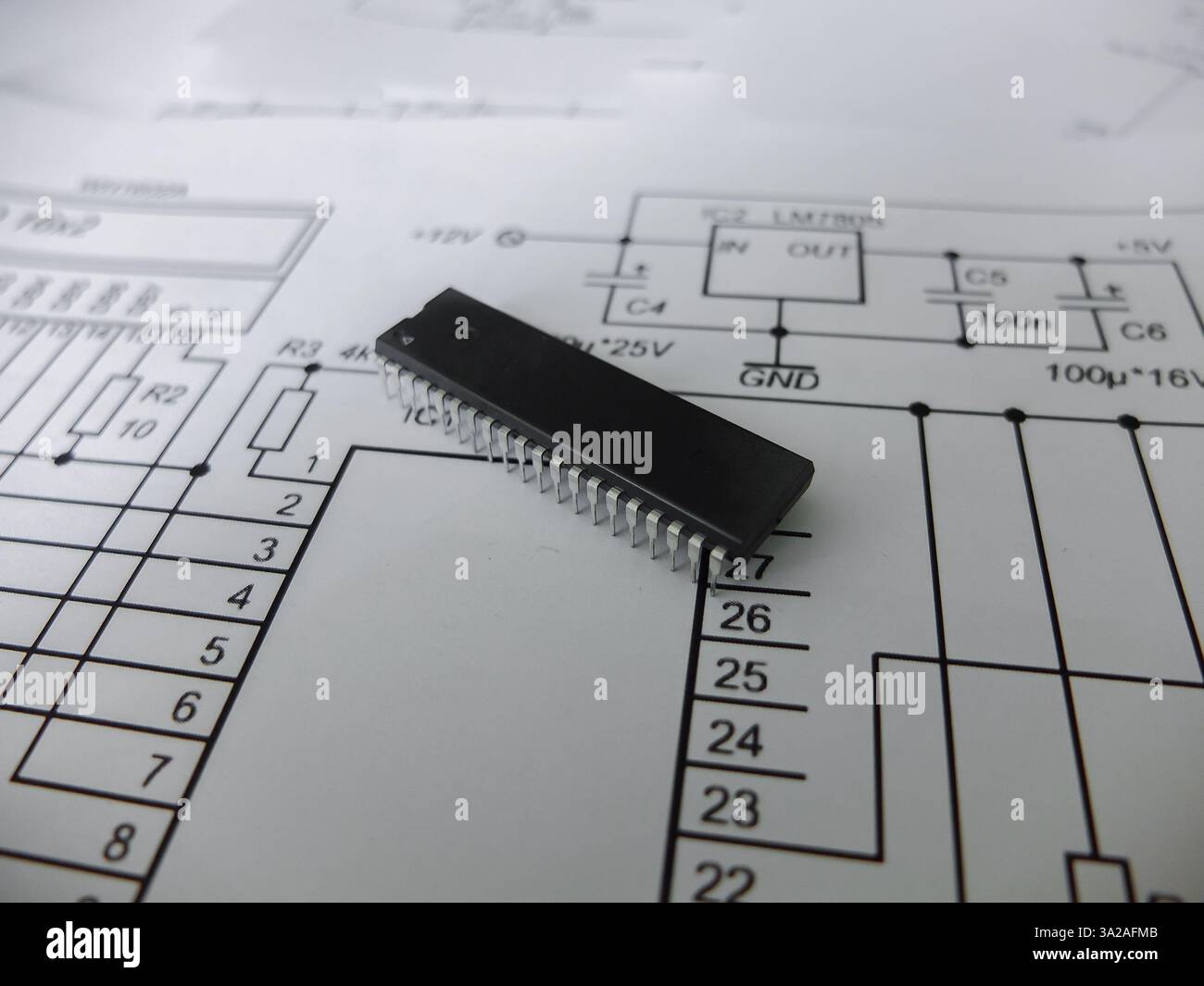 Verschiedene integrierte Schaltungen, Mikrocontroller in DIP-SOIC-TQFP-Gehäusen. Auf der Rückseite befindet sich ein Schaltplan Stockfoto