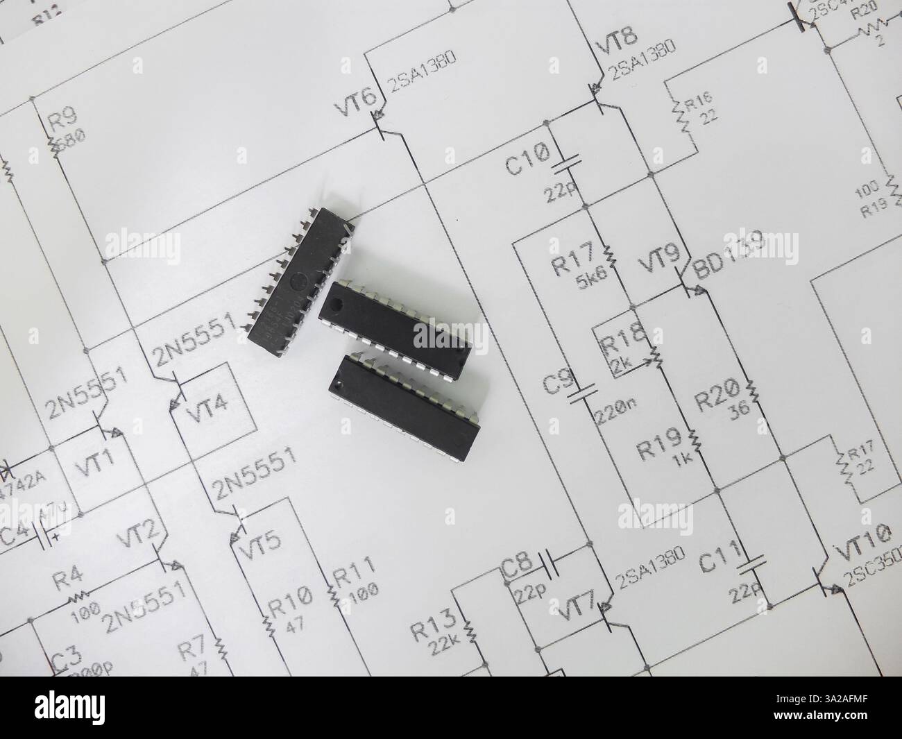 Verschiedene integrierte Schaltungen, Mikrocontroller in DIP-SOIC-TQFP-Gehäusen. Auf der Rückseite befindet sich ein Schaltplan Stockfoto