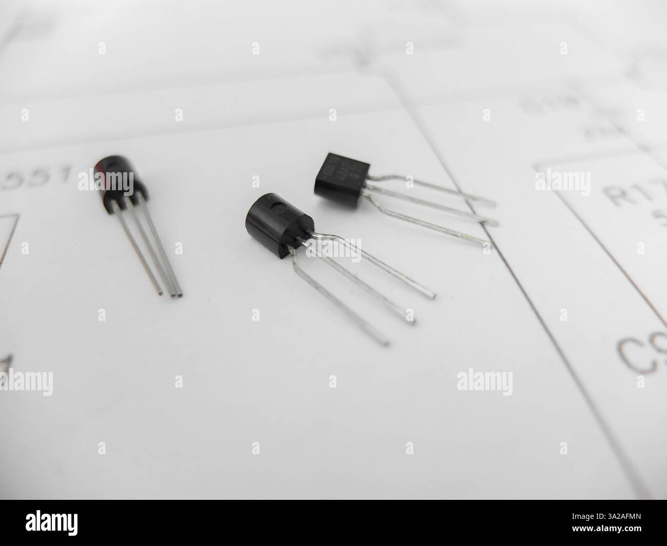 Verschiedene integrierte Schaltungen, Mikrocontroller in DIP-SOIC-TQFP-Gehäusen. Auf der Rückseite befindet sich ein Schaltplan Stockfoto