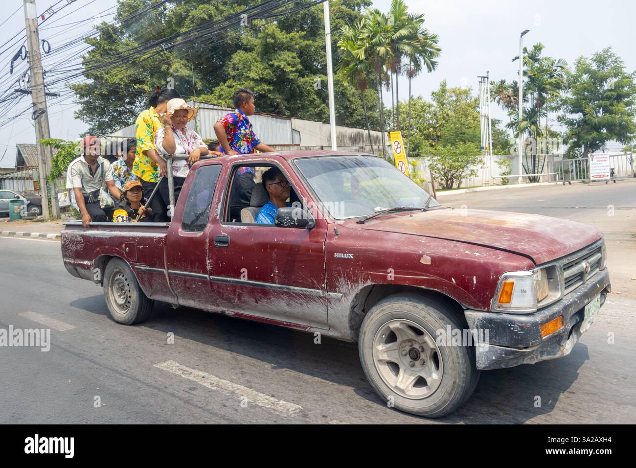 BANGKOK, THAILAND, 13. April 2024, fährt ein alter Pickup-Truck durch die Stadt mit einem Laderaum voller Menschen, die das Songkran Wasserfestival feiern Stockfoto