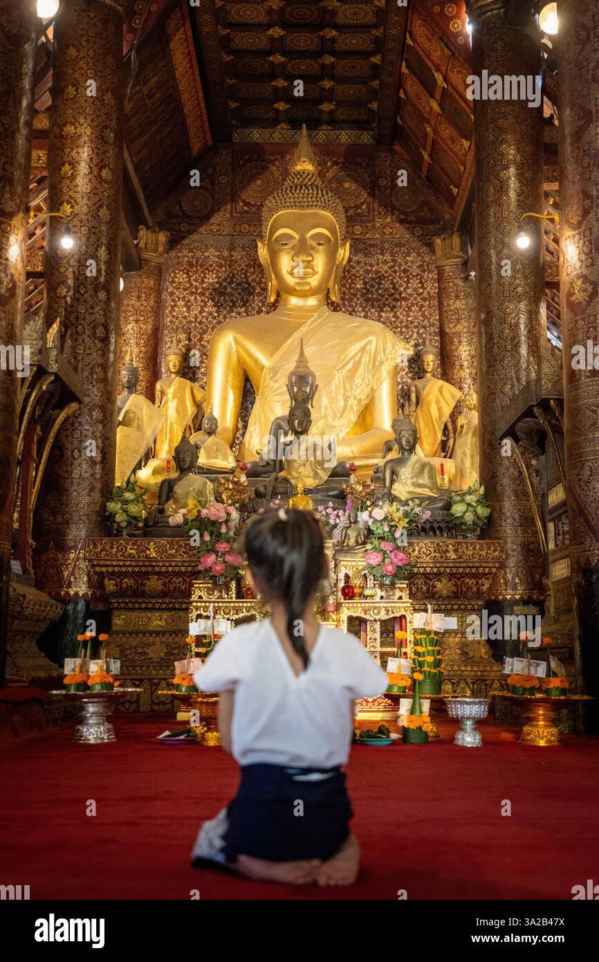 Mädchen betet im Wat Xieng Thong, Luang Prabang, Laos. Buddhistische Anbetung, Tempelinnere. Stockfoto
