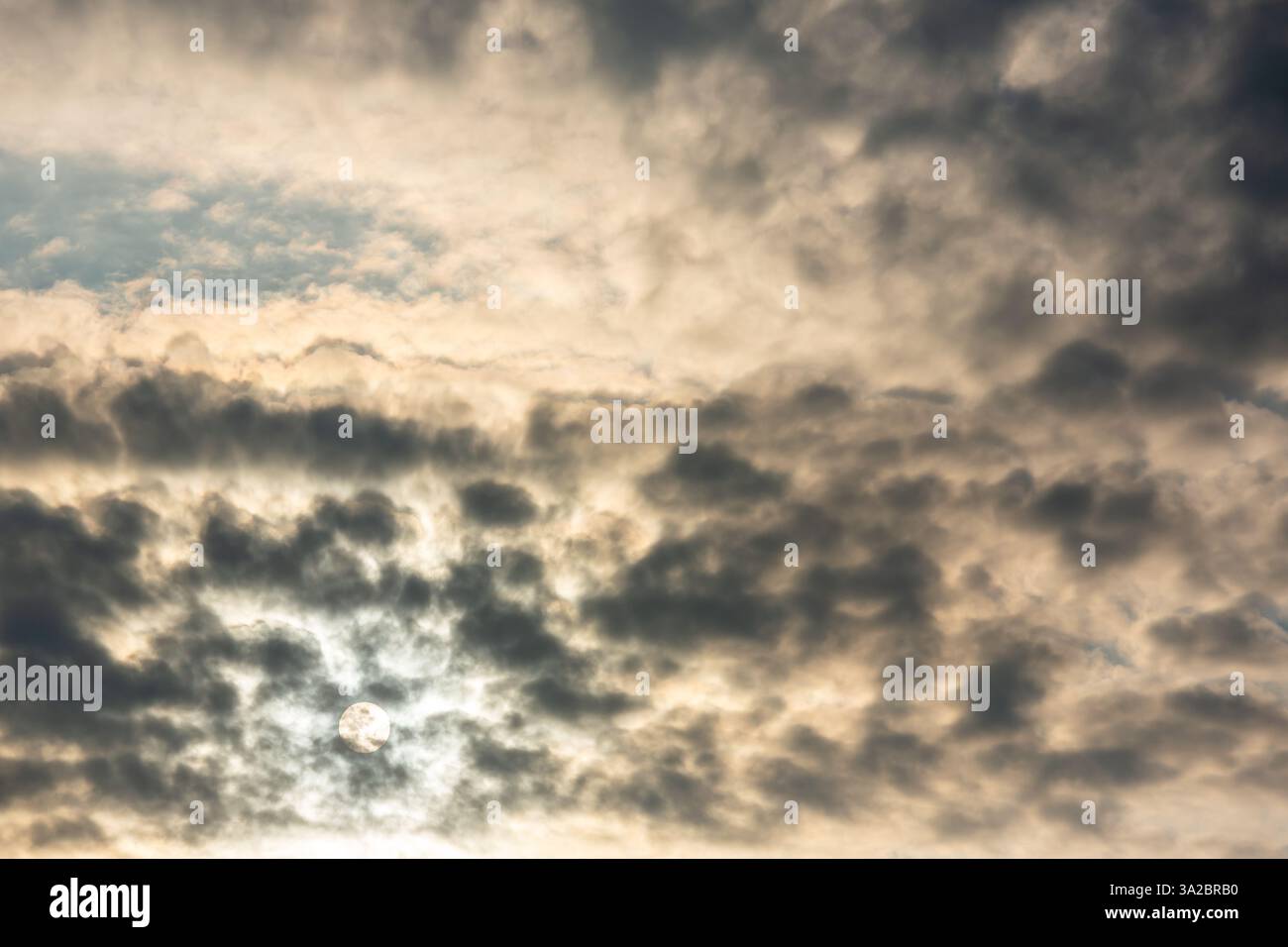 Die Sonne scheint schwach durch dicke, strukturierte Wolken und schafft einen dramatischen und stimmungsvollen Himmel mit kontrastierenden Licht und Schatten. Stockfoto Die Sonne scheint schwach durch dicke, strukturierte Wolken und schafft einen dramatischen und stimmungsvollen Himmel mit kontrastierenden Licht und Schatten. Stockfoto