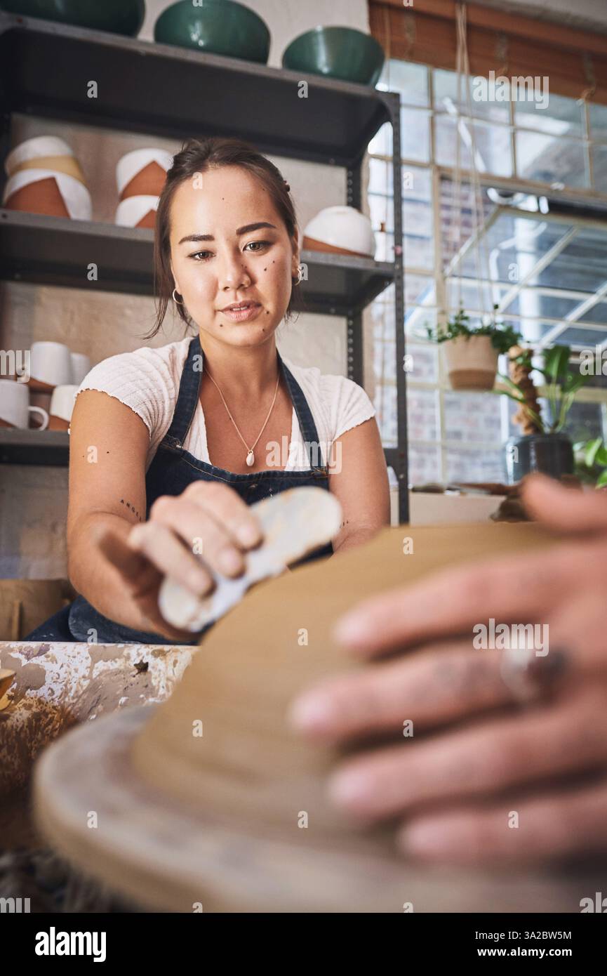 Menschen-, Werkzeug- und Töpferunterricht im Atelier, arbeiten zusammen und schnitzen Ton für keramisches Handwerk. Unterricht, Ausrüstung und Hilfe beim Unterricht an Stockfoto