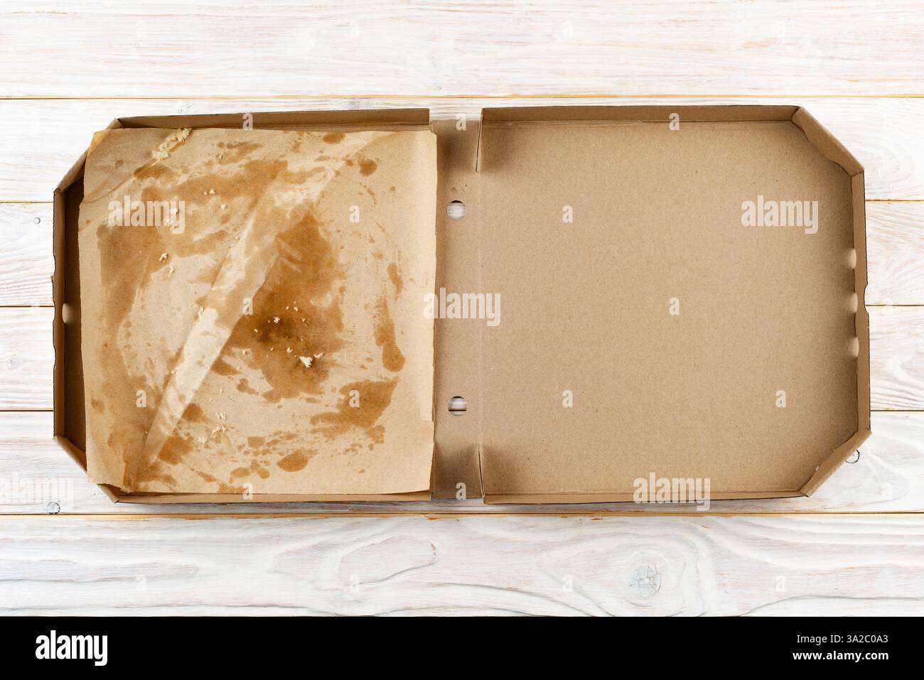 Leere Pizzaschachtel mit Brotkrumen auf weißem Holztisch mit flacher Ladefläche Stockfoto