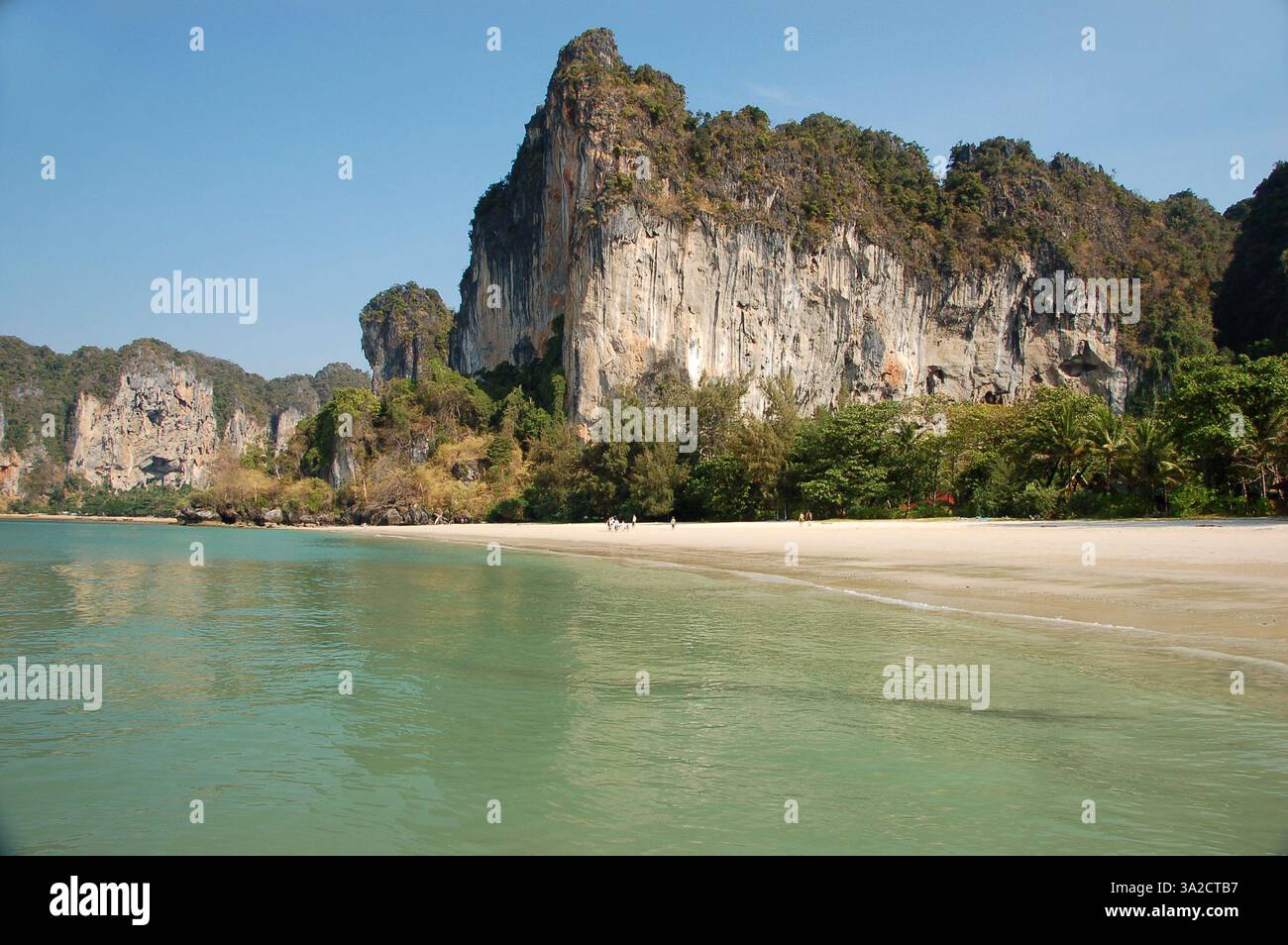 Ein atemberaubender Blick auf Railay Beach, Thailand, mit hoch aufragenden Kalksteinklippen, üppigem Grün und türkisfarbenem Wasser unter einem klaren blauen Himmel Stockfoto