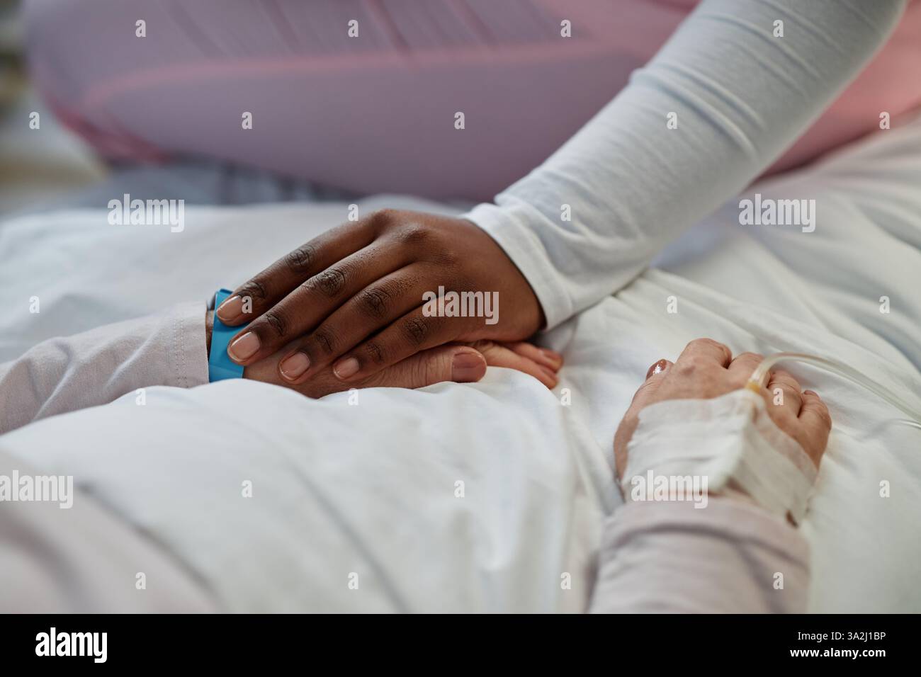 Mitfühlende Berührung zwischen den Händen des Patienten im Krankenhaus. Sanfte Haltegeste für Komfort und emotionale Unterstützung während der Erholung Stockfoto