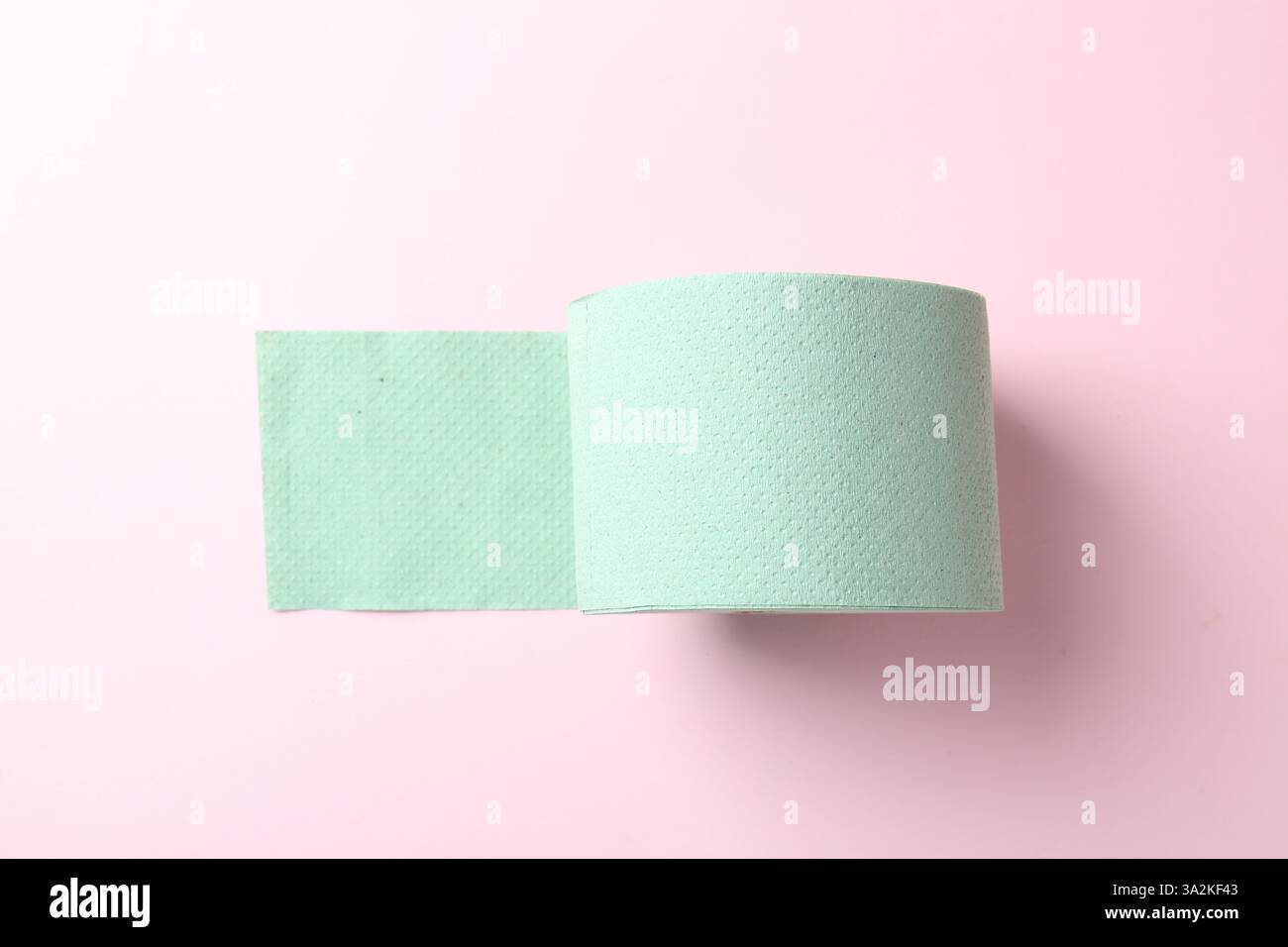 Grüne Toilettenpapierrolle auf hellrosa Hintergrund, Draufsicht Stockfoto