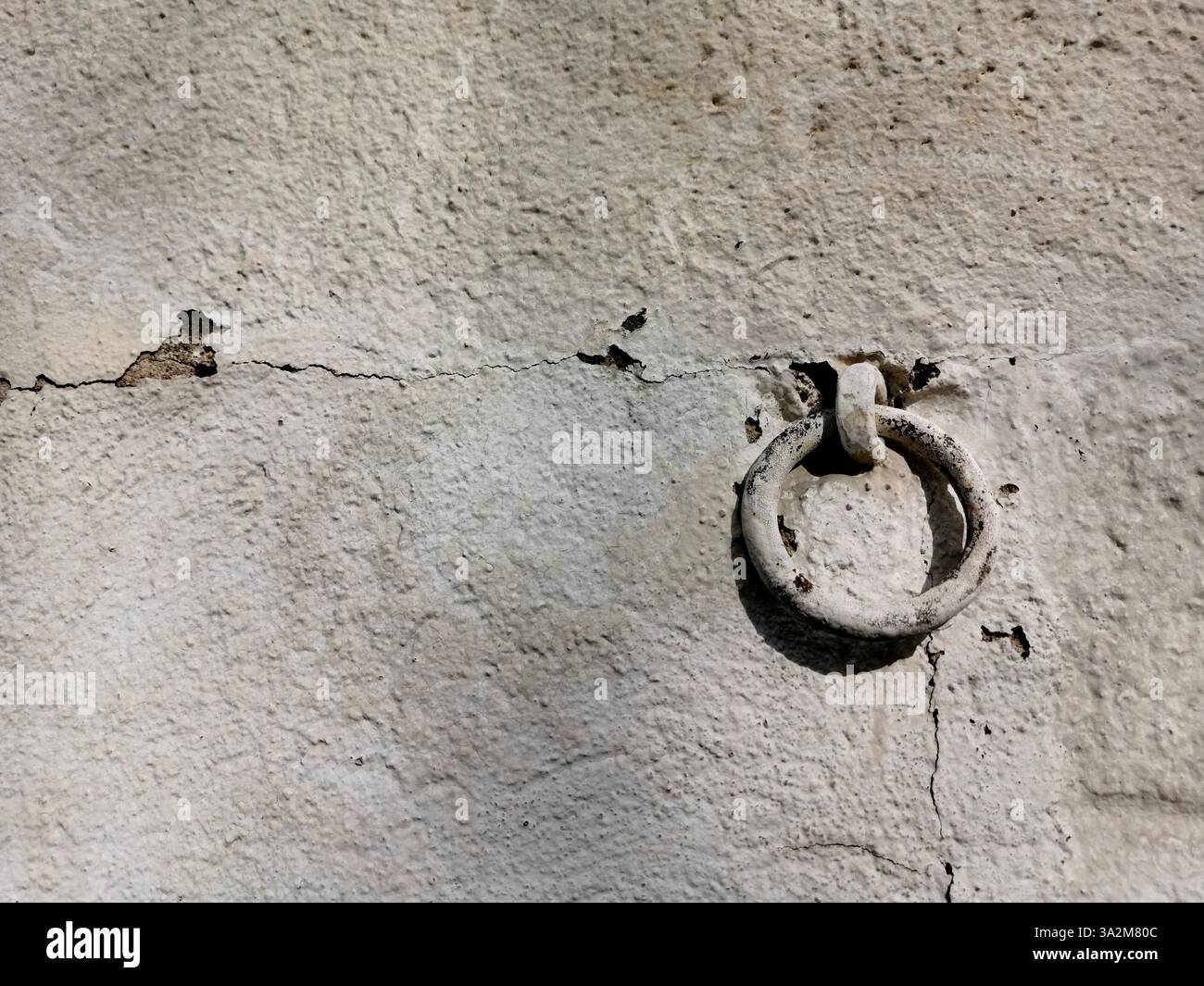 Verwitterte Wand mit eisernem Ring, der Textur und historischen Charme in einer städtischen Umgebung zeigt Stockfoto