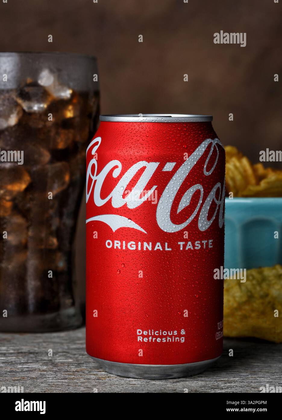 IRVINE, KALIFORNIEN - 12. März 2025: Nahaufnahme einer Coca-Cola-Dose mit Kondenswasser mit einem Glas Limonade und einer Schüssel Chips dahinter. Stockfoto