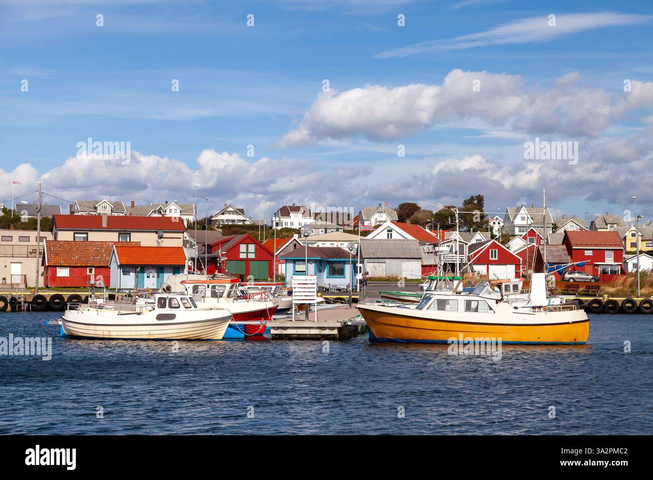 Ein malerischer Blick auf Borhaug, Lista in Norwegen, bietet einen ruhigen Hafen mit blauem Wasser und ordentlich angeordneten Booten. Traditionelle rote und weiße Häuser Stockfoto