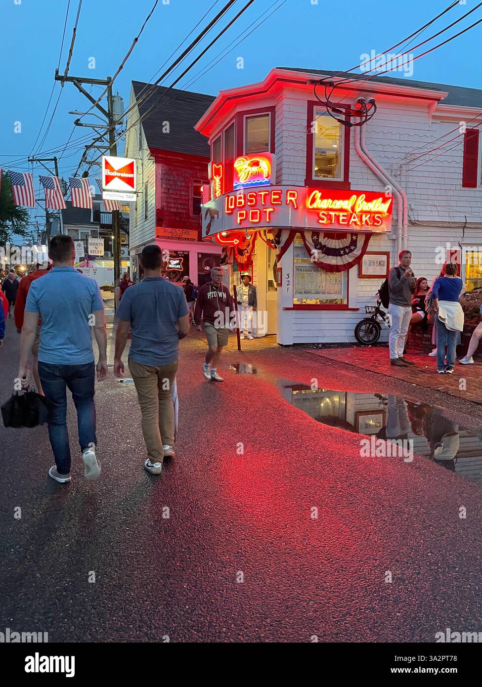 Die Menschen genießen einen warmen Sommerabend in der Innenstadt von Provincetown Massachusetts auf Cape Cod, vorbei am Lobster Pot, einem Fischrestaurant mit leuchtendem Neonschild Stockfoto