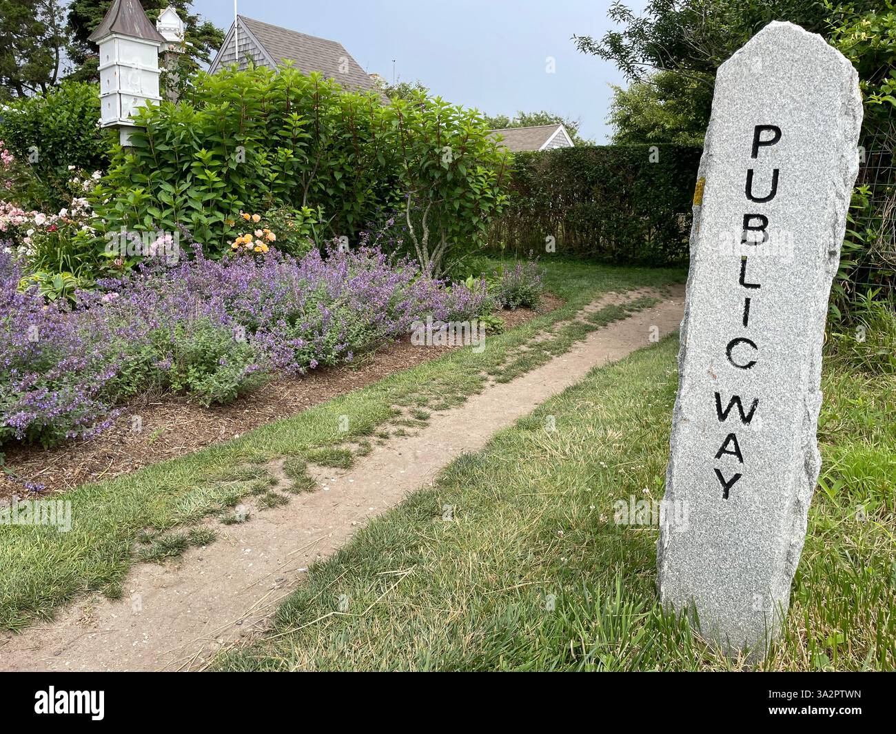 Eine Steinsäule markiert den Weg eines öffentlichen Spaziergangs, der an einem Garten in Siasconset auf Nantucket Island vorbeiführt Stockfoto