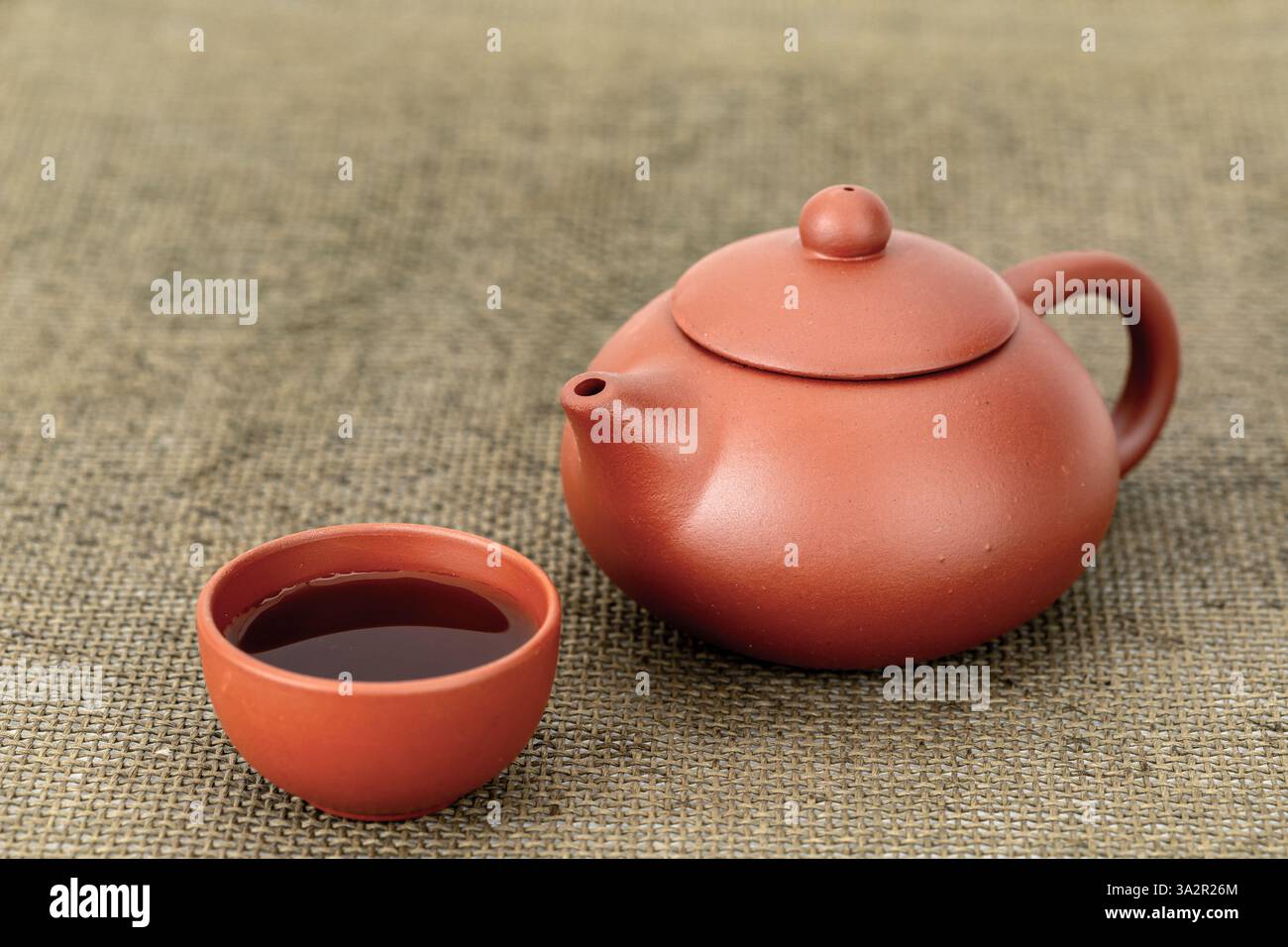 Traditionelle chinesische Teekanne mit Ziegelsteinen und Tassen mit Tee auf einem Tisch. Stockfoto