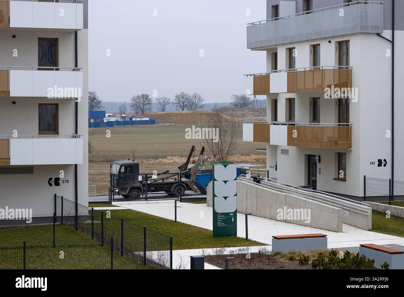 Breslau, Polen, 12. Februar 2025: Zeitgenössisches Wohngebiet mit Wohnhäusern und einem Müllwagen, der einen Müllcontainer aufnimmt Stockfoto