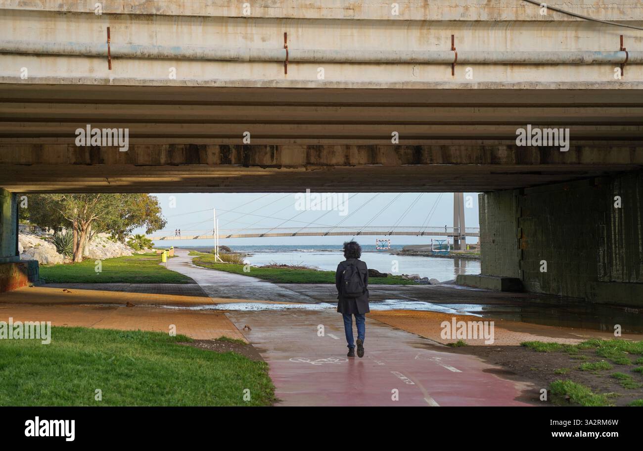 Eine Frau läuft unter einer Brücke am Fluss Fuengirola, Costa del Sol, Spanien. Stockfoto