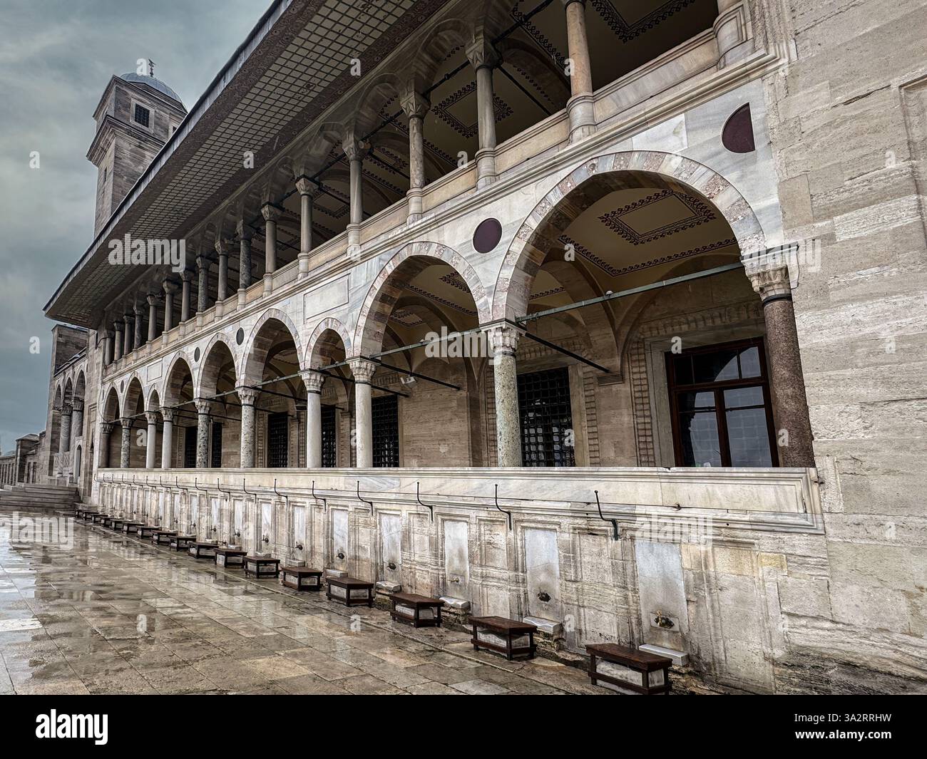 Eine prächtige historische Moschee mit eleganten Bogensäulen und detaillierten Ziersteinmauern unter einem bewölkten Himmel, Istanbul, Türkei Stockfoto