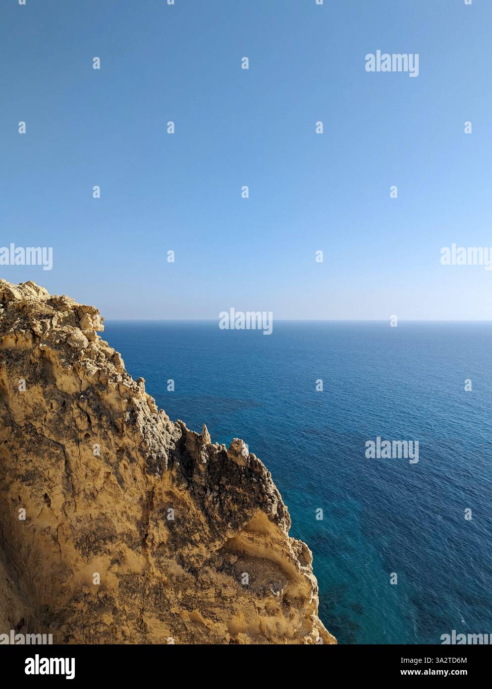 Goldene Klippen erheben sich über endlos blauem Kap Aspro und bieten einen friedlichen Blick auf den mediterranen Horizont. Stockfoto