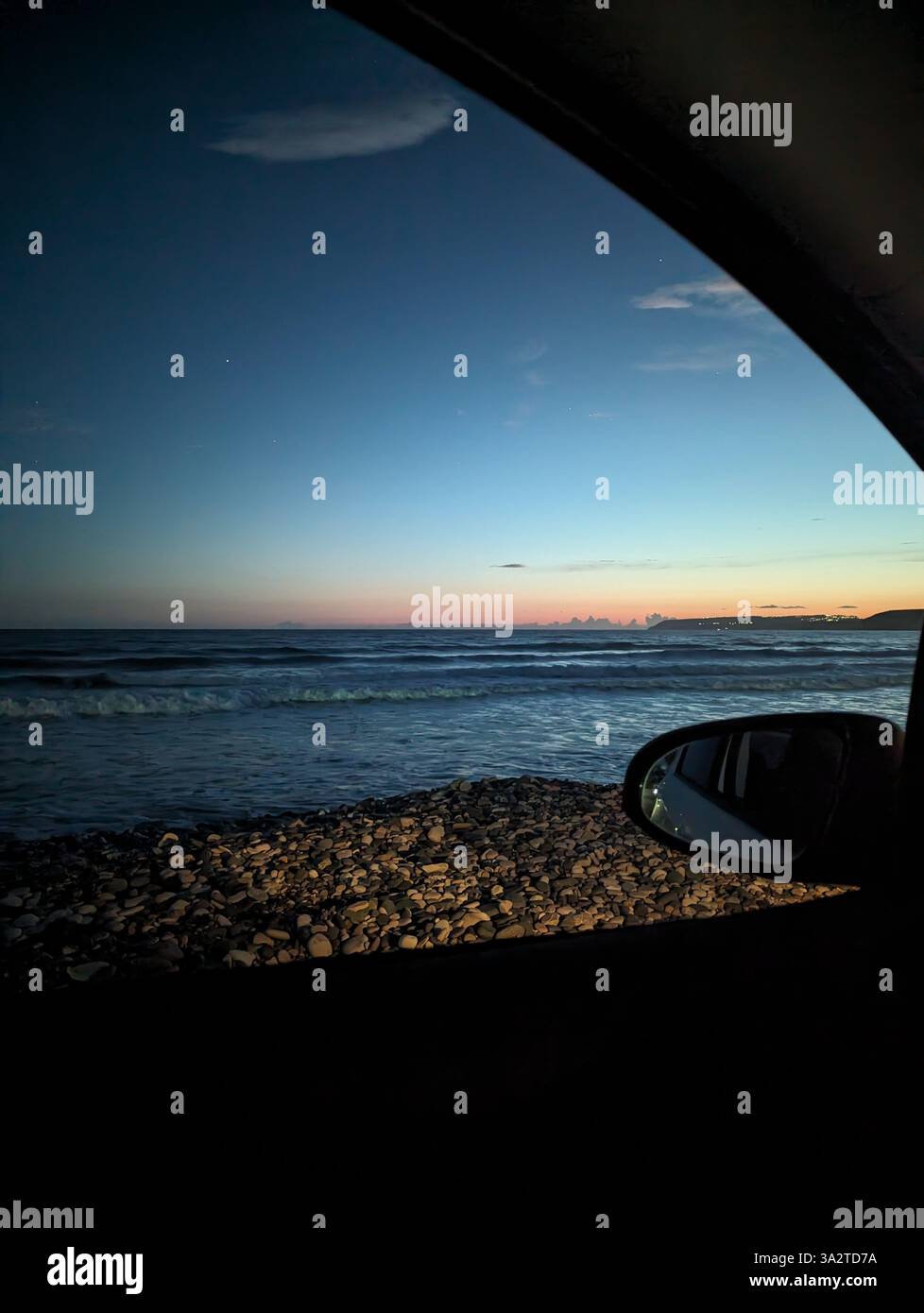 Abendlicher Blick auf Kourion Beach in Zypern, von einem geparkten Auto aus aufgenommen, während das letzte Licht über dem Meer verblasst. Stockfoto