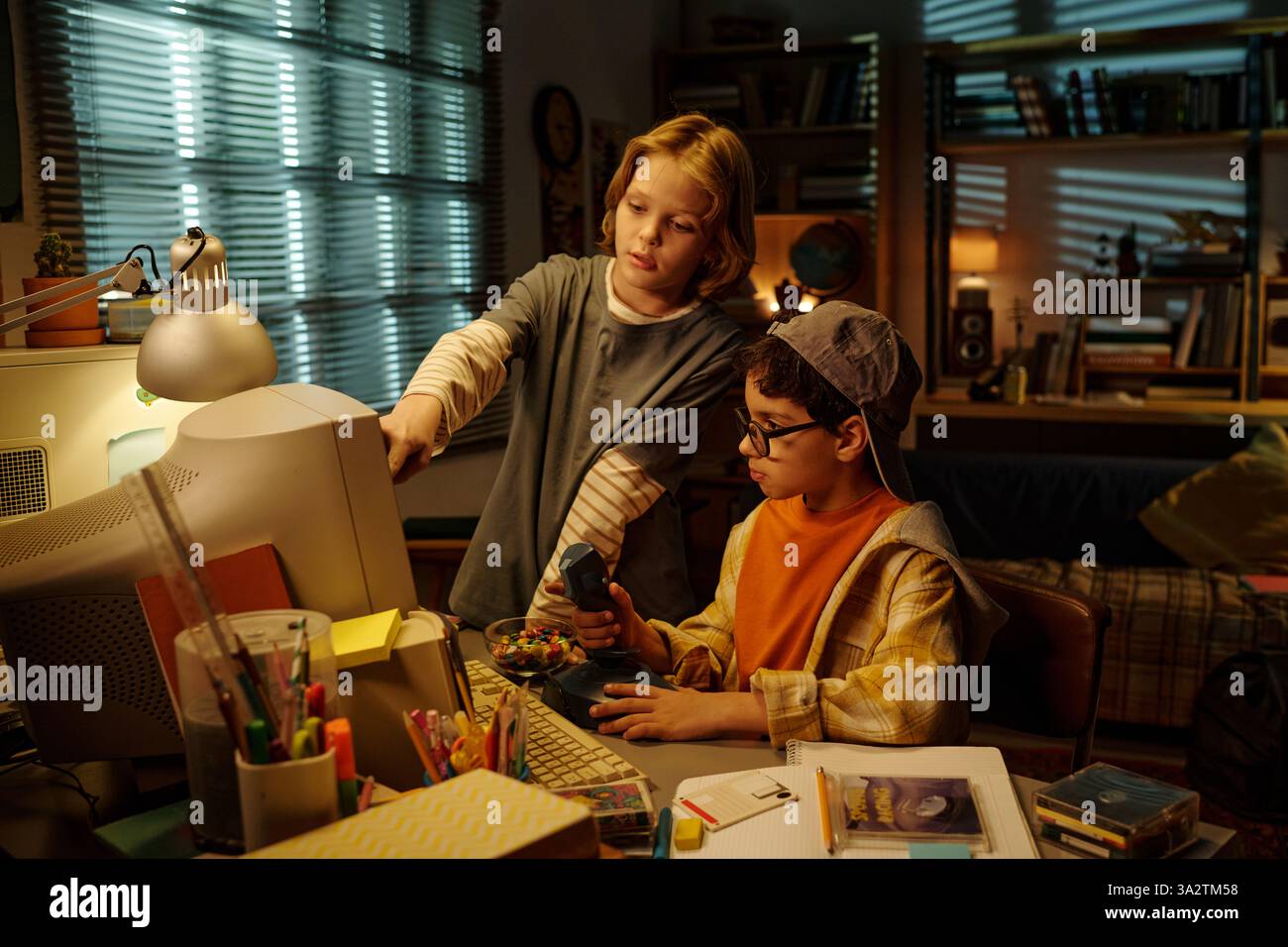 Kinder erkunden Retro-Technologie in einem gemütlichen Wohnzimmer mit Bücherregalen, Lampen und anderen Vintage-Dekoren, die eine ansprechende, lehrreiche Atmosphäre schaffen Stockfoto