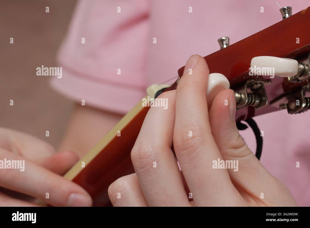 Extrem Nahaufnahme weiblicher Finger, die spanische 6-saitige Akustikgitarre stimmen, die Saiten spannen und lockern, bevor sie mit dem klassischen Gitarrenspiel beginnen. Stockfoto