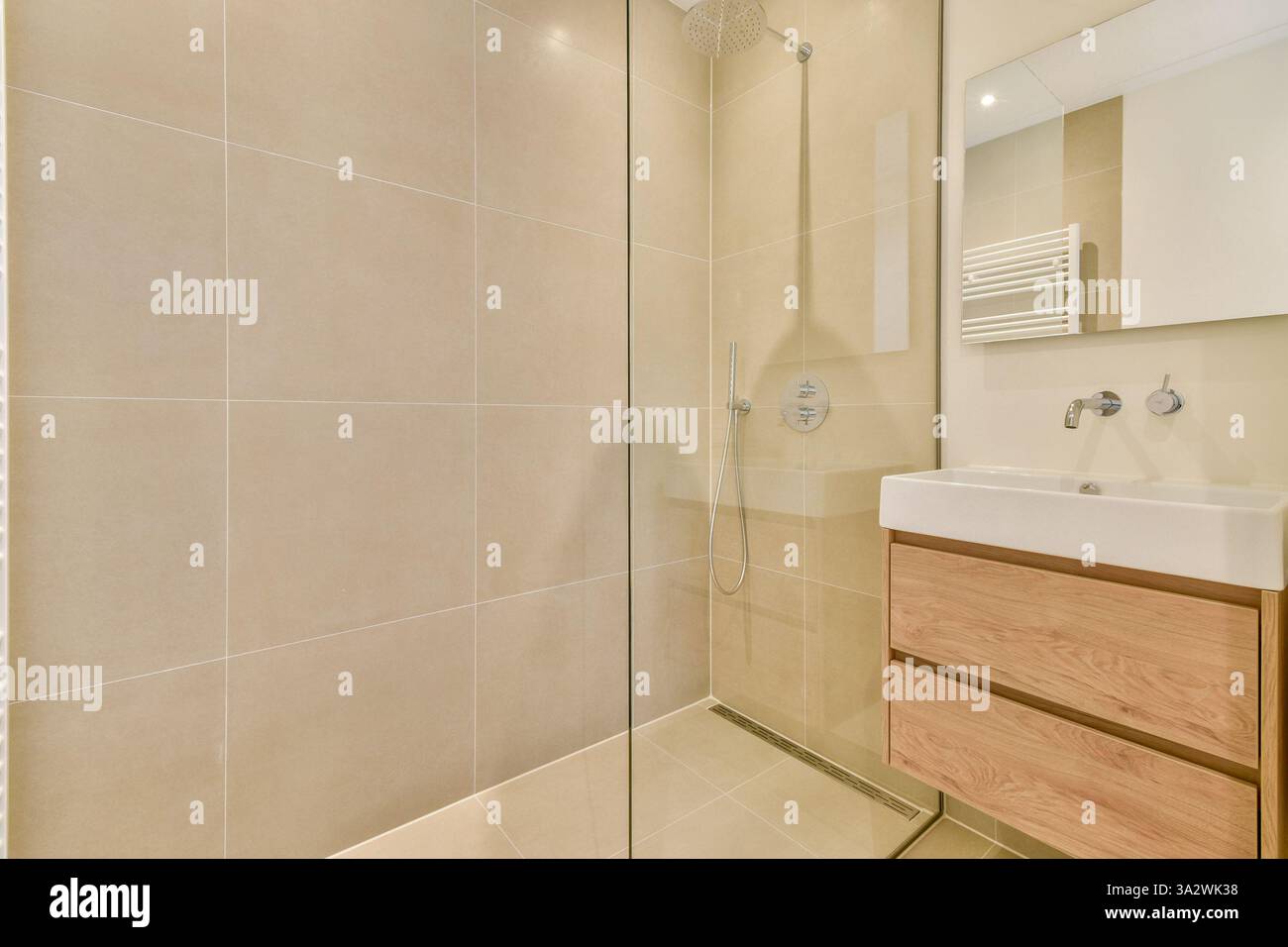 Ein stilvolles, modernes Duschbad mit Glasgehäuse, eleganten Fliesen und einem Kosmetikbereich aus Holz. Es wurde für ein modernes Wohnen mit einer Mischung aus Eleganz und Funktionalität entworfen. Stockfoto