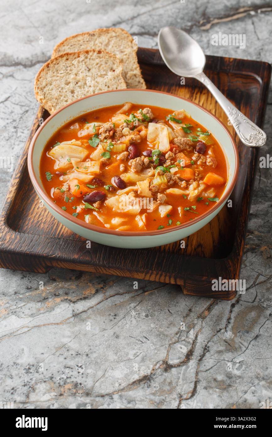 Rindfleisch und Kohl Suppe ist gefüllt mit gewürztem Hackfleisch, Kohl, Karotten, Sellerie, Kidneybohnen, und Tomatenwürfel in der Nähe auf dem Teller auf dem Tisch Stockfoto