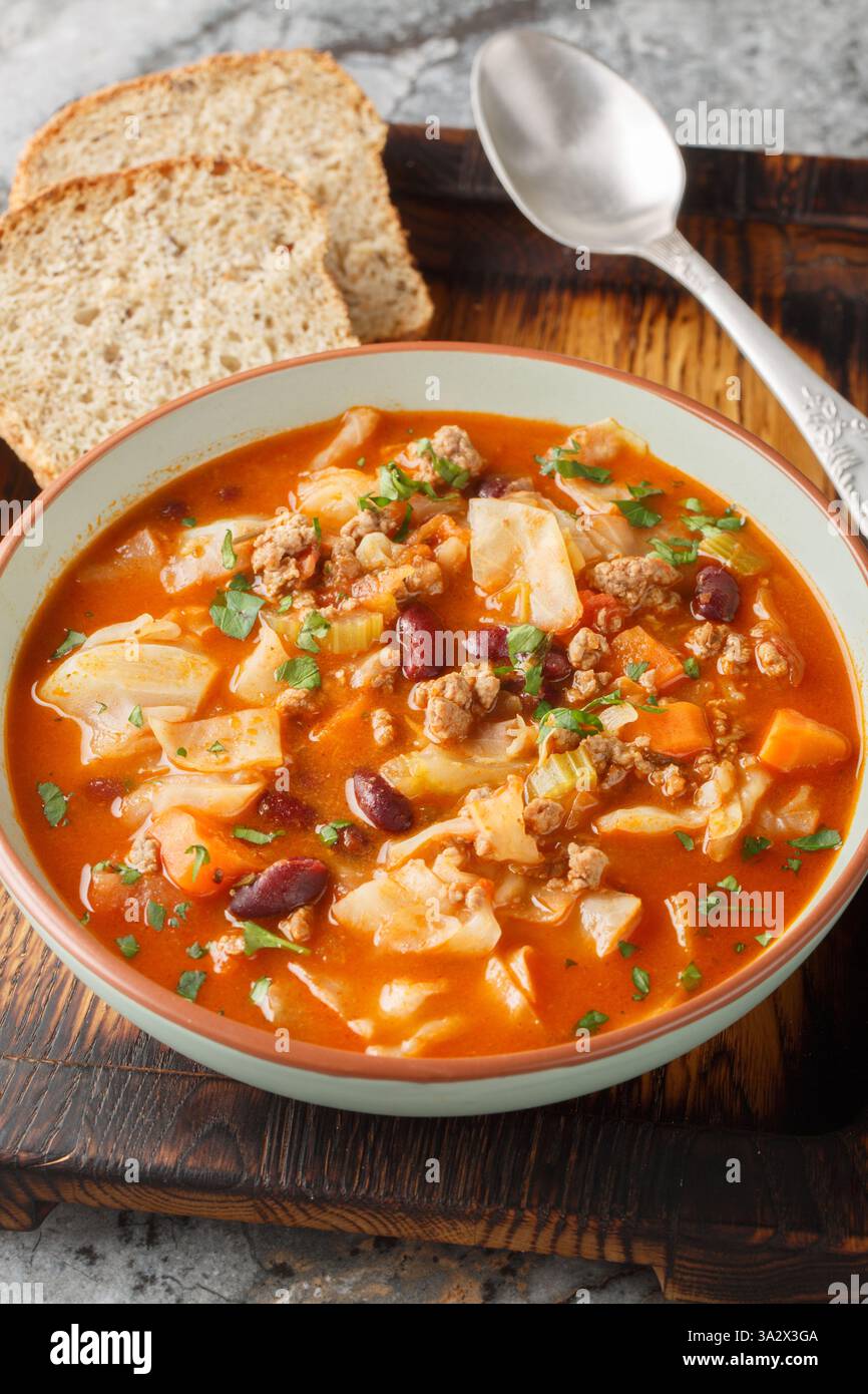 Gemahlene Rinderkohl-Suppe, mit roten Bohnen, Zwiebeln, Tomaten, Karotten und Sellerie aus der Nähe auf dem Teller auf dem Tisch. Vertikal Stockfoto