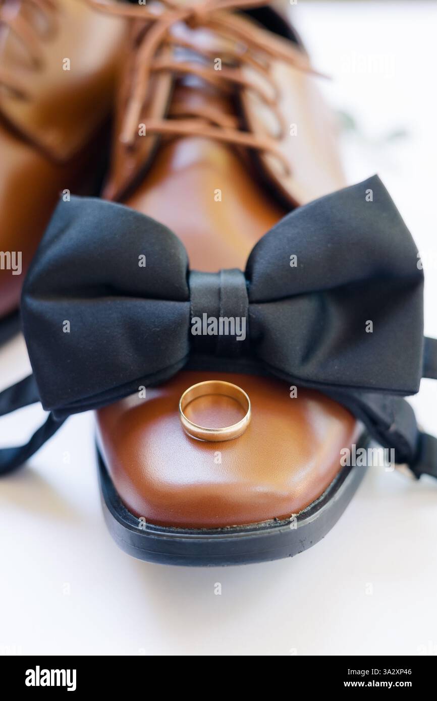 Brauner Lederschuh mit schwarzer Schleife und goldenem Ehering oben. Stockfoto