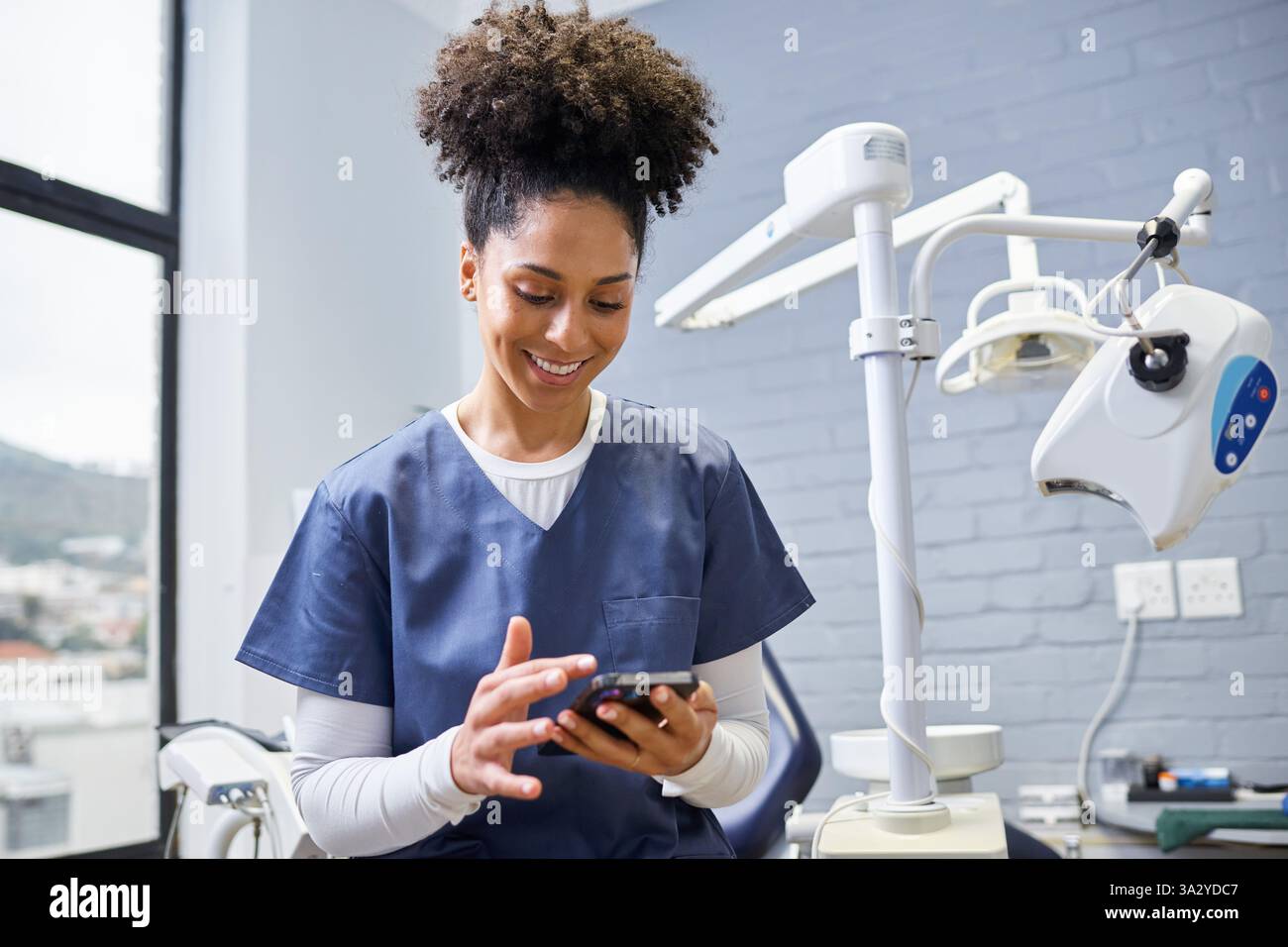 Lächelnde Zahnärztin mit Smartphone in einer modernen Zahnklinik Stockfoto