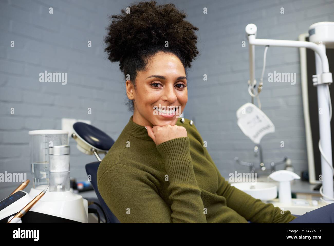 Lächelnde Frau, die sich in einer Zahnklinik neben medizinischen Geräten entspannt Stockfoto