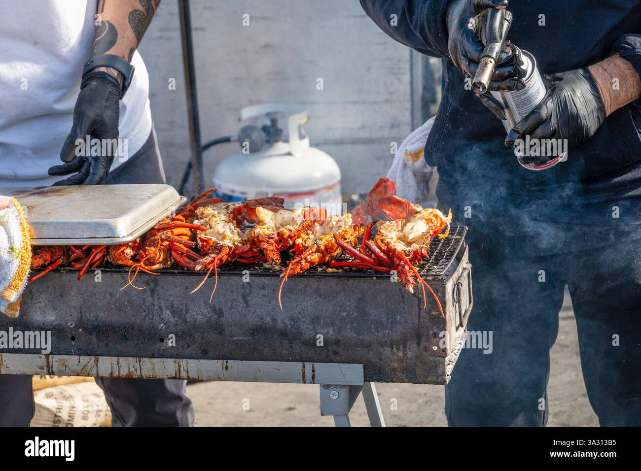 Man grillt Hummer am Thuna Harbor Dockside Market in San Diego, Kalifornien, Charring the Hummer with A Blow Fackel, 15. Februar 2025 Stock Photo Stockfoto