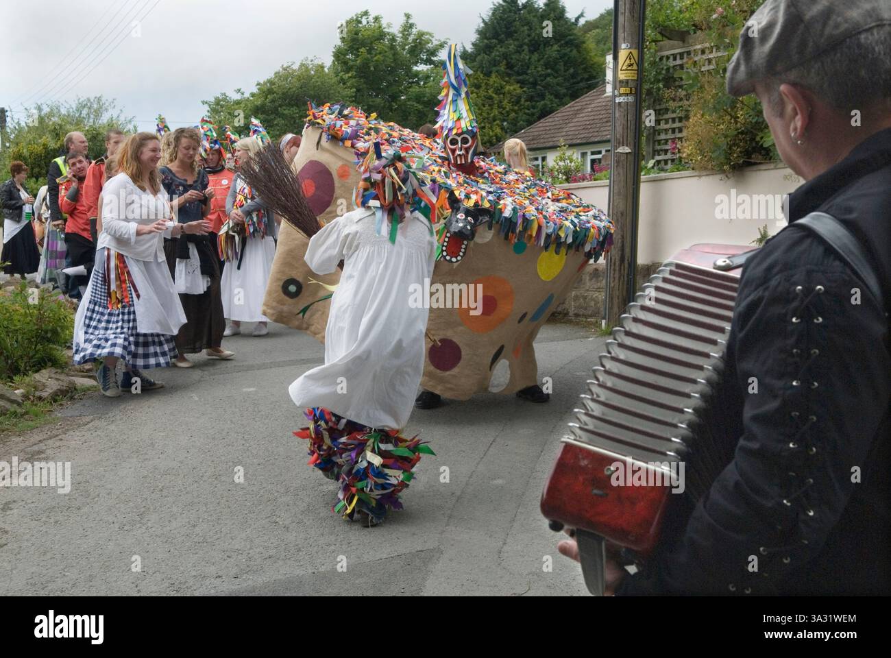 Hobby Horse With the Teaser (zurück zur Kamera) führt die Obby Oss tanzend durch Combe Martin während des jährlichen Sommerfestes Bank Holiday Weekend. Menschenmassen von Dorfbewohnern sprechen am jährlichen Festival. Jagd auf den Earl of Rone. Combe Martin, Mid Devon England, Mai 2011 UK 2010s HOMER SYKES. Stockfoto