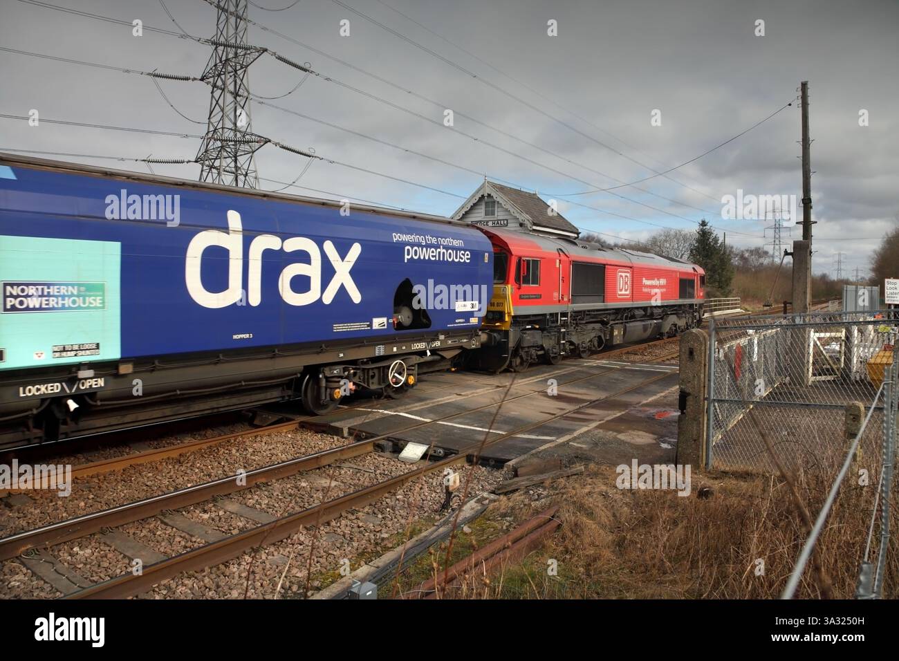 Die DB Cargo Class 66 Lok 66077 passiert die Bahnüberquerung von Medge Hall mit dem 1038 4R50 Milford Anschlussgleis zum Immingham Leere Biomasse-Zug am 25.02.25. Stockfoto
