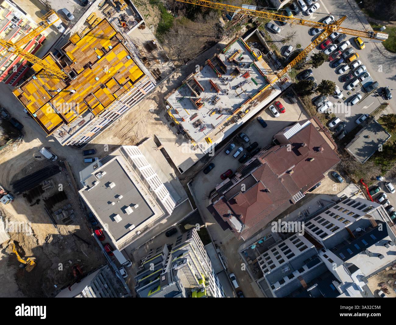 Auf der Baustelle werden in einem städtischen Gebiet unter hellem Sonnenlicht leuchtende Materialien und Geräte präsentiert. Draufsicht der Antenne Stockfoto