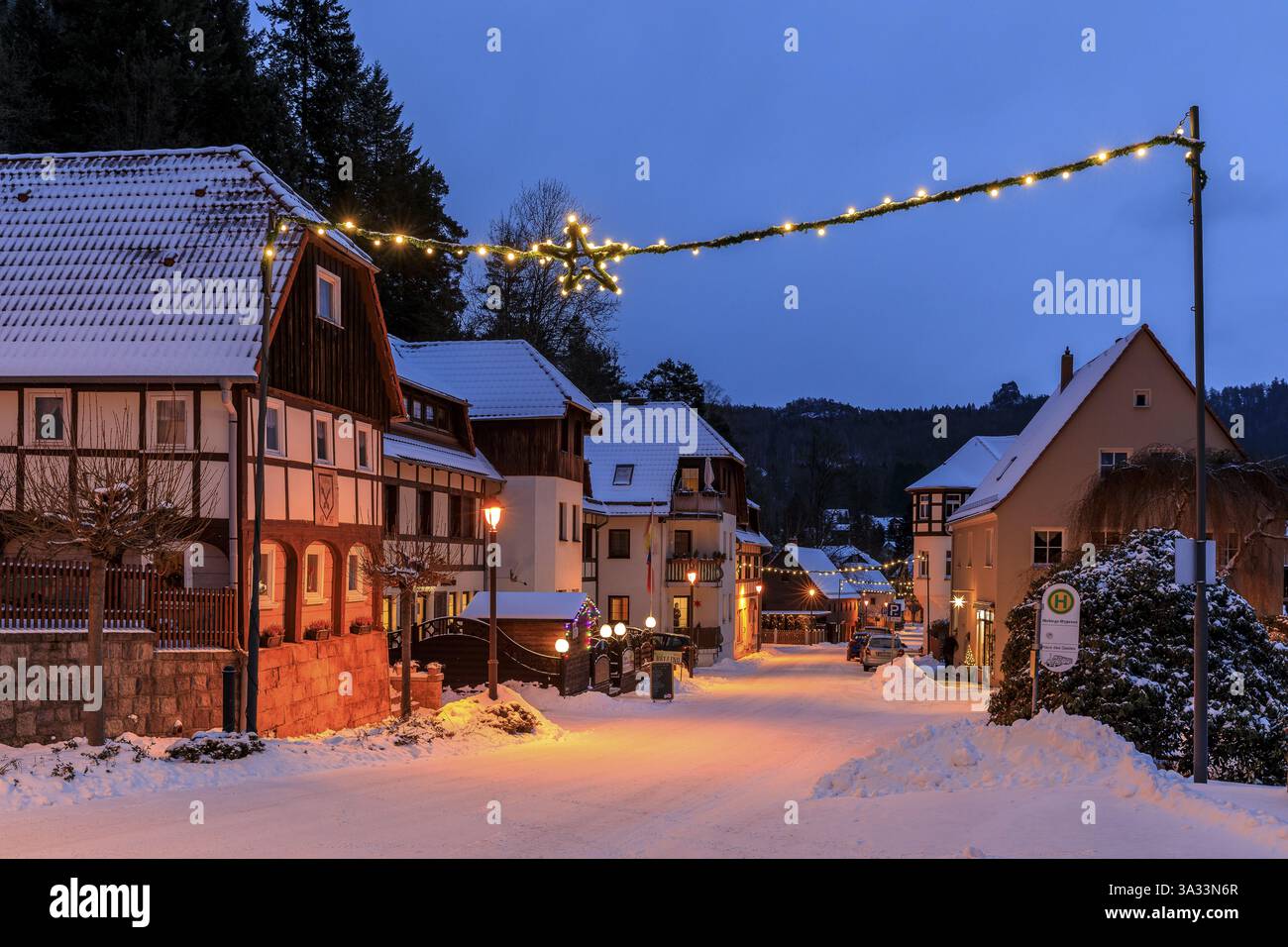 Schneebedeckte Hauptstraße in der Abenddämmerung mit Weihnachtsschmuck, Oybin, Zittauer Berge, Sachsen, Deutschland, Europa Stockfoto