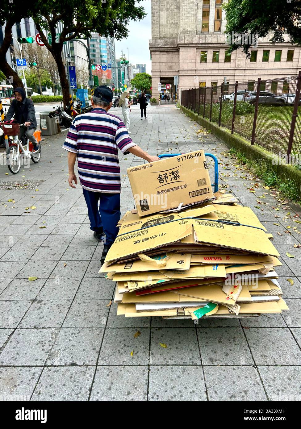 Taipei, Taiwan, Wanderarbeitnehmer, Mann, von hinten, sammelt recycelten Müll Karton, auf der Straße, geht auf dem Bürgersteig weg - Smartphone-aufgenommenes Stockfoto