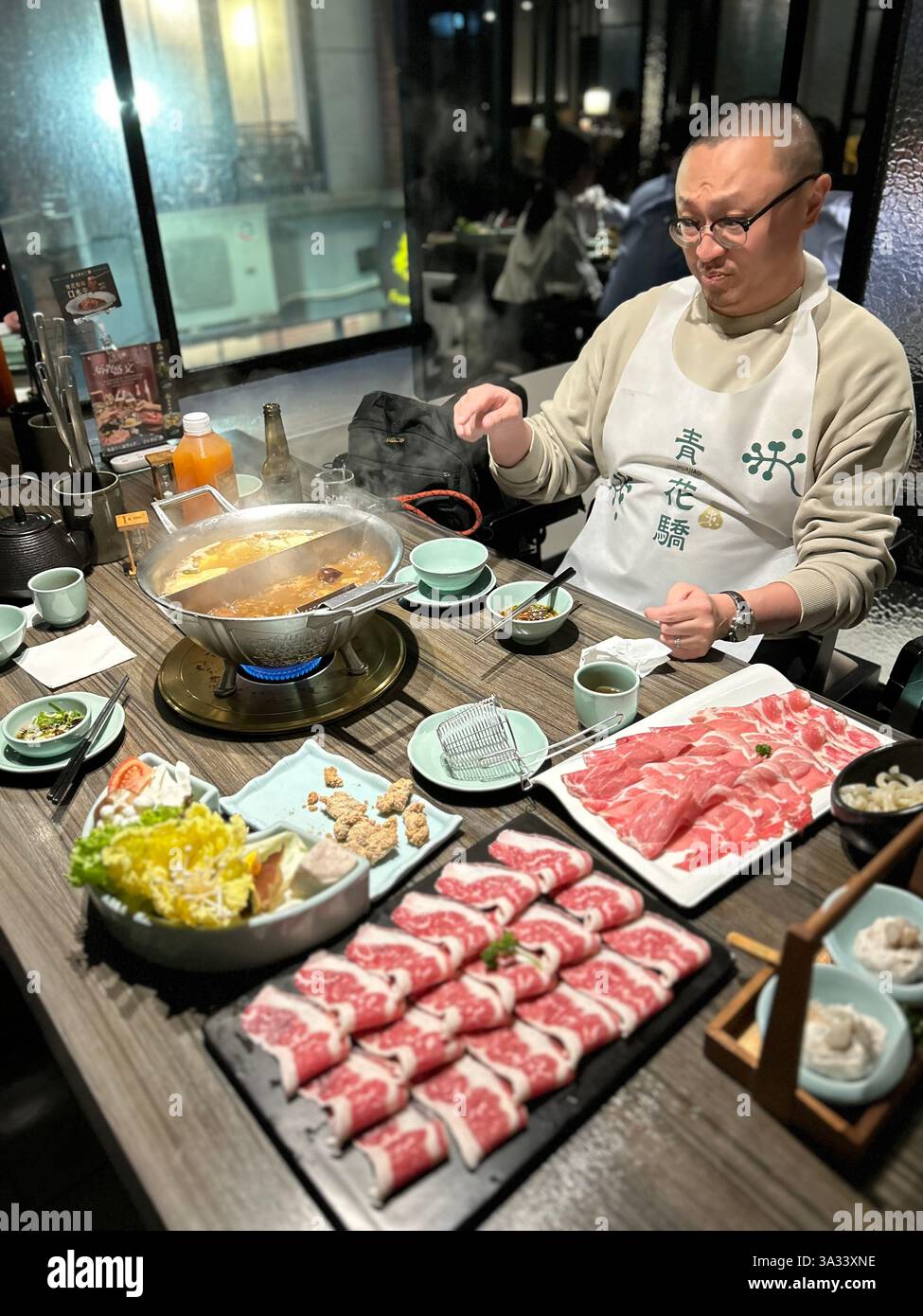Taipei, Taiwan, chinesischer Tourist am Tisch, innen, im lokalen taiwanesischen Hot Pot Restaurant, 'Chin Huajiao » essen Fleisch - Smartphone-aufgenommenes Stockfoto