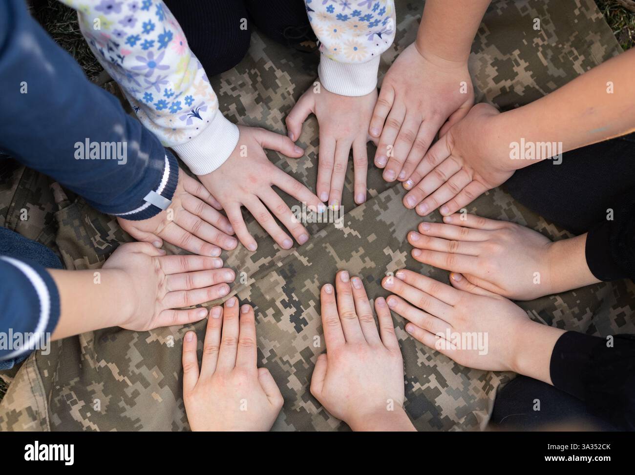Einige Kinder haben die Hände auf Pixel Uniform. Mit Liebe zu den Verteidigern der Ukraine. Konzept der Einheit und Unterstützung. Stoppt den Krieg. Stockfoto