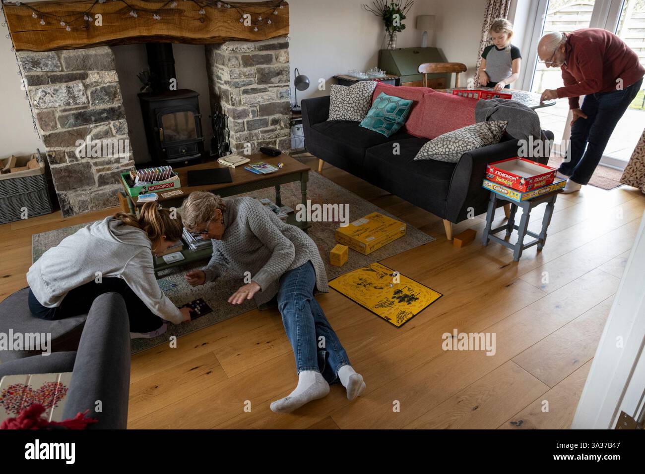 Mädchen im Alter von 9 Jahren (links) und 7 Jahren, die mit ihren Großeltern zu Hause an Aktivitäten teilnahmen. Der 9-Jährige spielt ein Brettspiel und der jüngere arbeitet Stockfoto