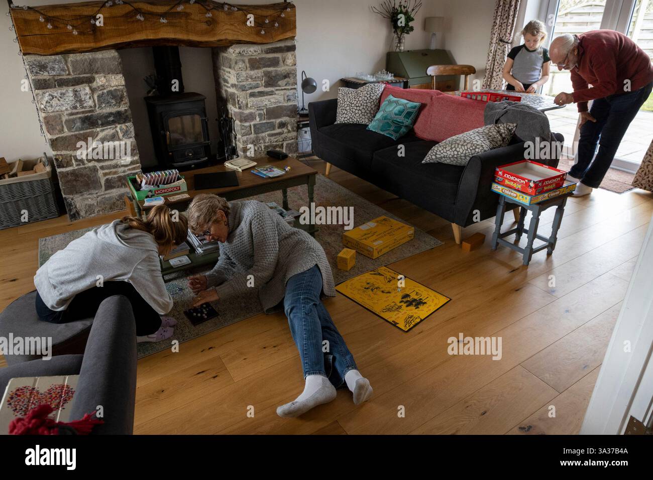 Mädchen im Alter von 9 Jahren (links) und 7 Jahren, die mit ihren Großeltern zu Hause an Aktivitäten teilnahmen. Der 9-Jährige spielt ein Brettspiel und der jüngere arbeitet Stockfoto