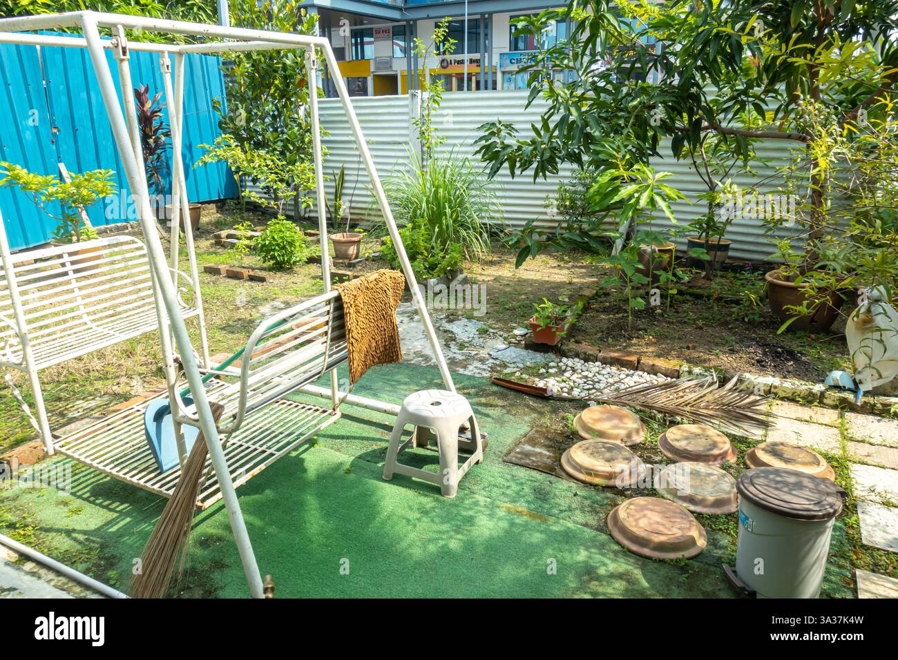 Eine Metallschaukel im Garten. Hinter der Schaukel, Pflanzen, Hof im traditionellen malaiischen Haus Melaka, Malaysia Stockfoto
