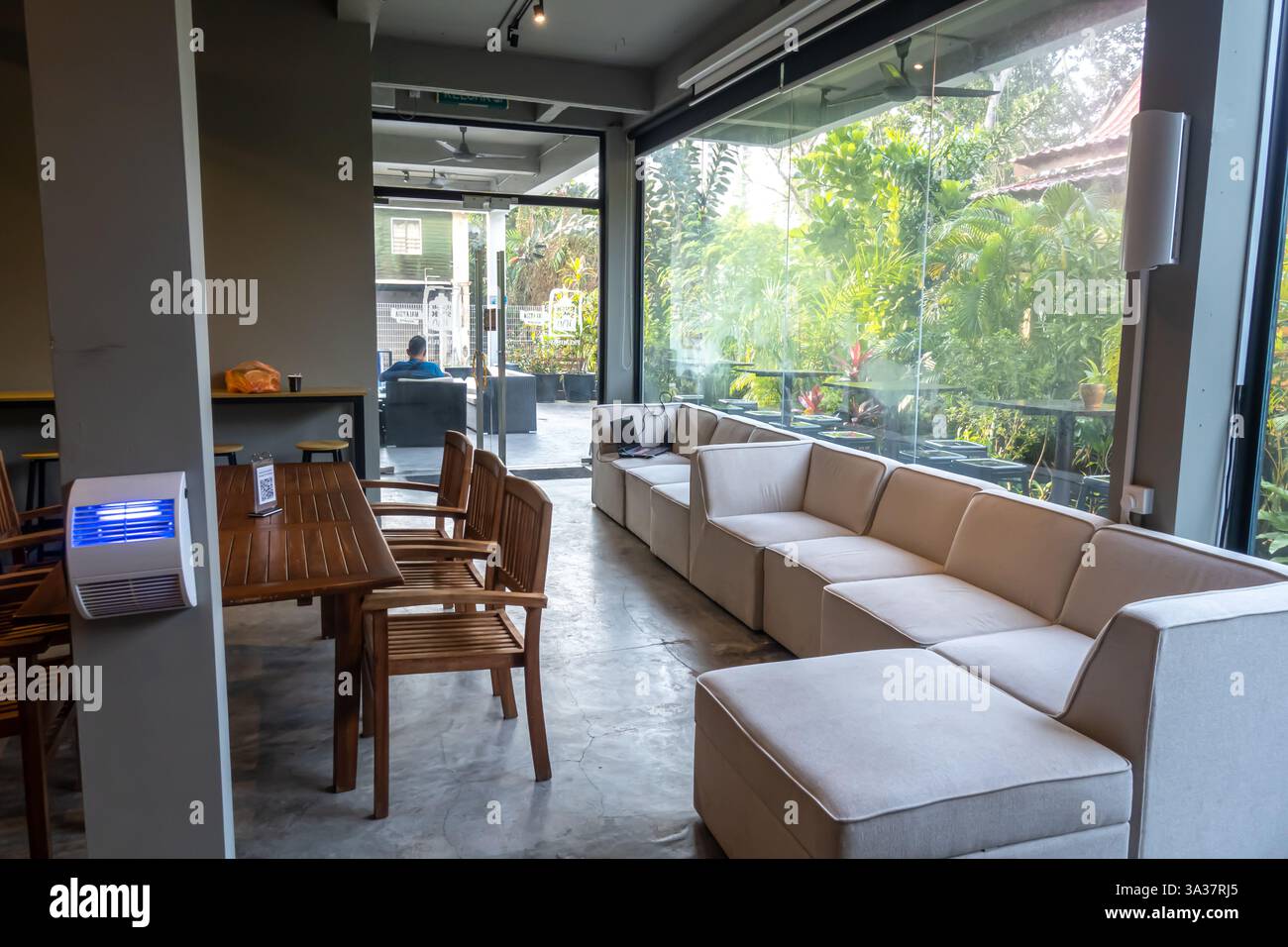Malaysisches Wohnzimmer im Hotel, Innenraum mit Sitzbereich und Essbereich. Sitzbereich, modulares Ecksofa, Fenster Stockfoto