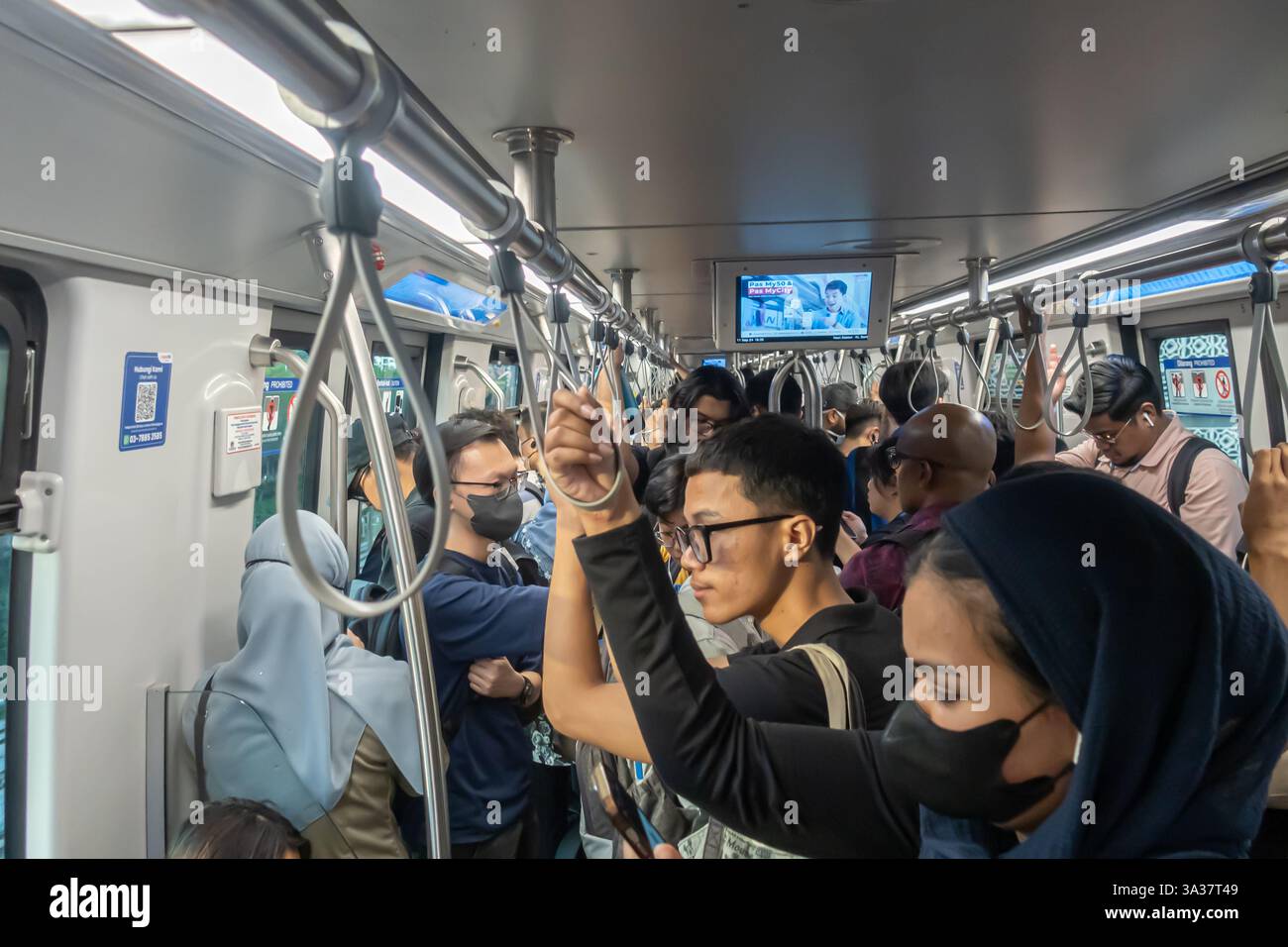 Überfüllte Zugwagen mit mehreren Fahrgästen, viele tragen Gesichtsmasken. Eine typische Pendelfahrt in einem städtischen Gebiet Kuala Lumpur, Malaysia Stockfoto
